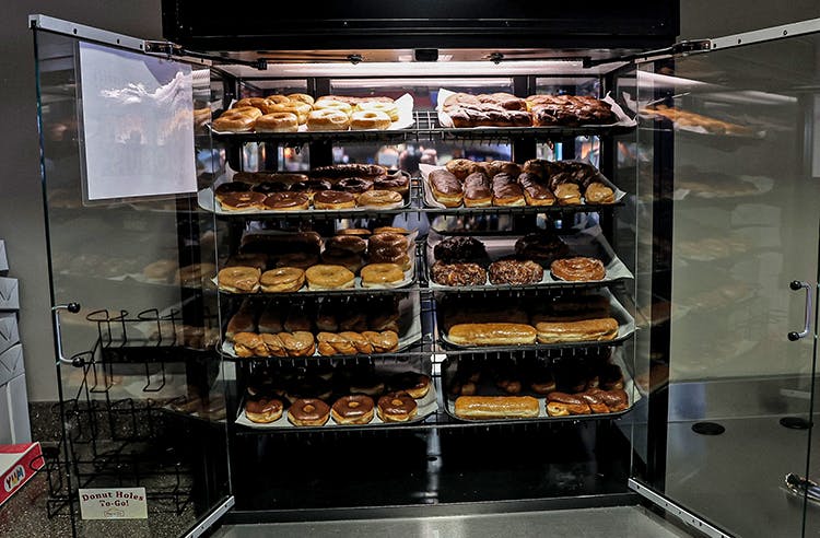 a glass display case filled with different kinds of donuts