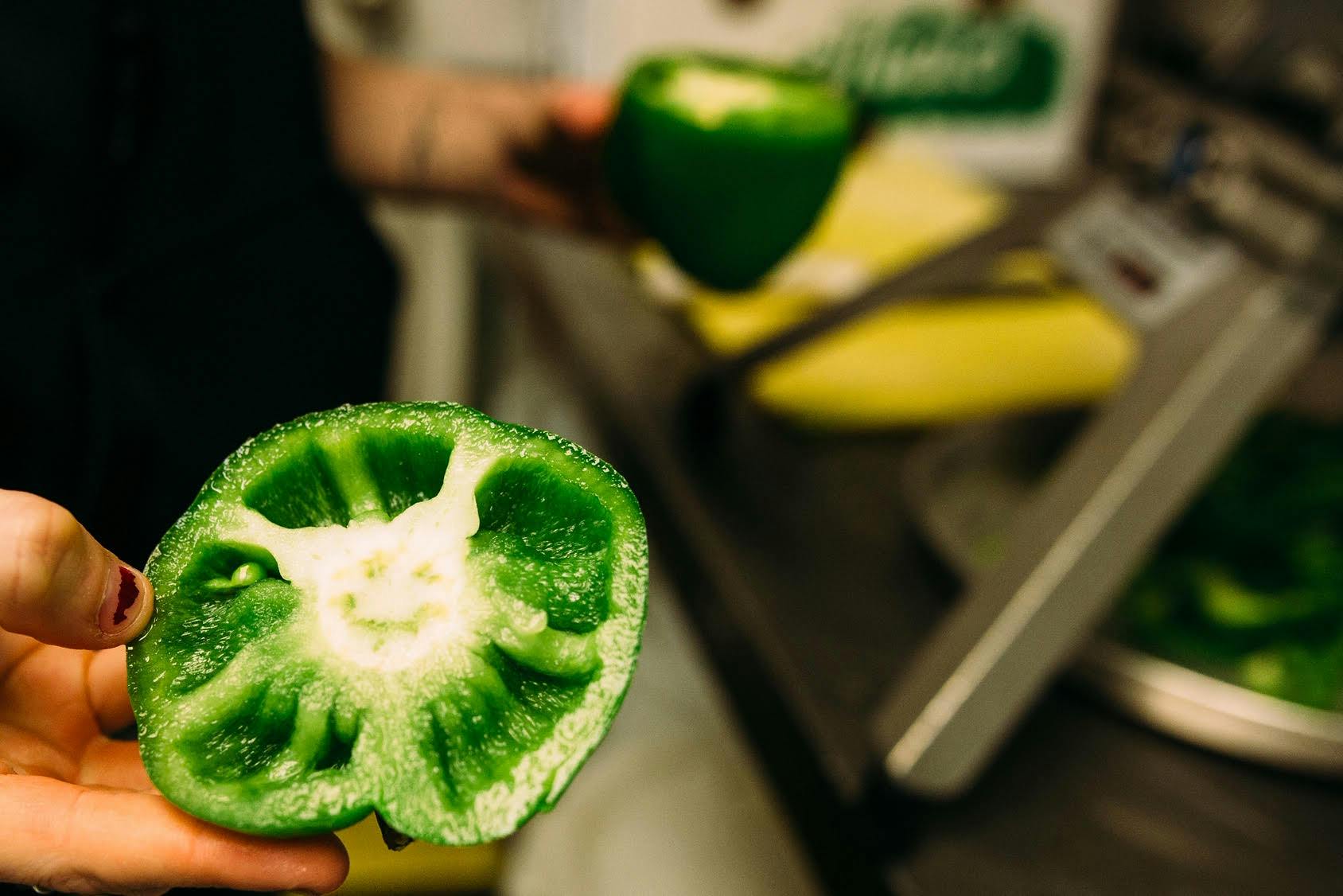 a close up of a hand holding a green pepper