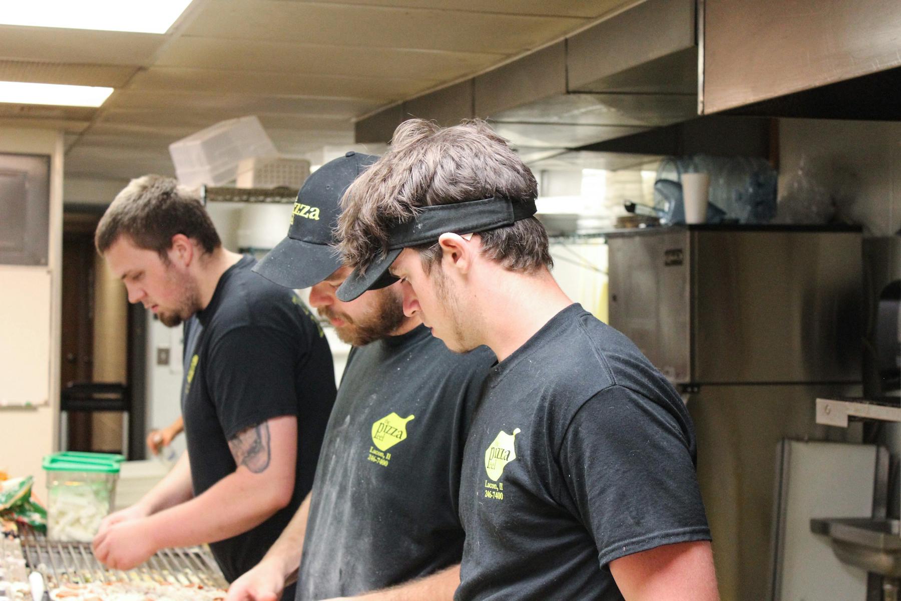 people standing in a kitchen preparing food