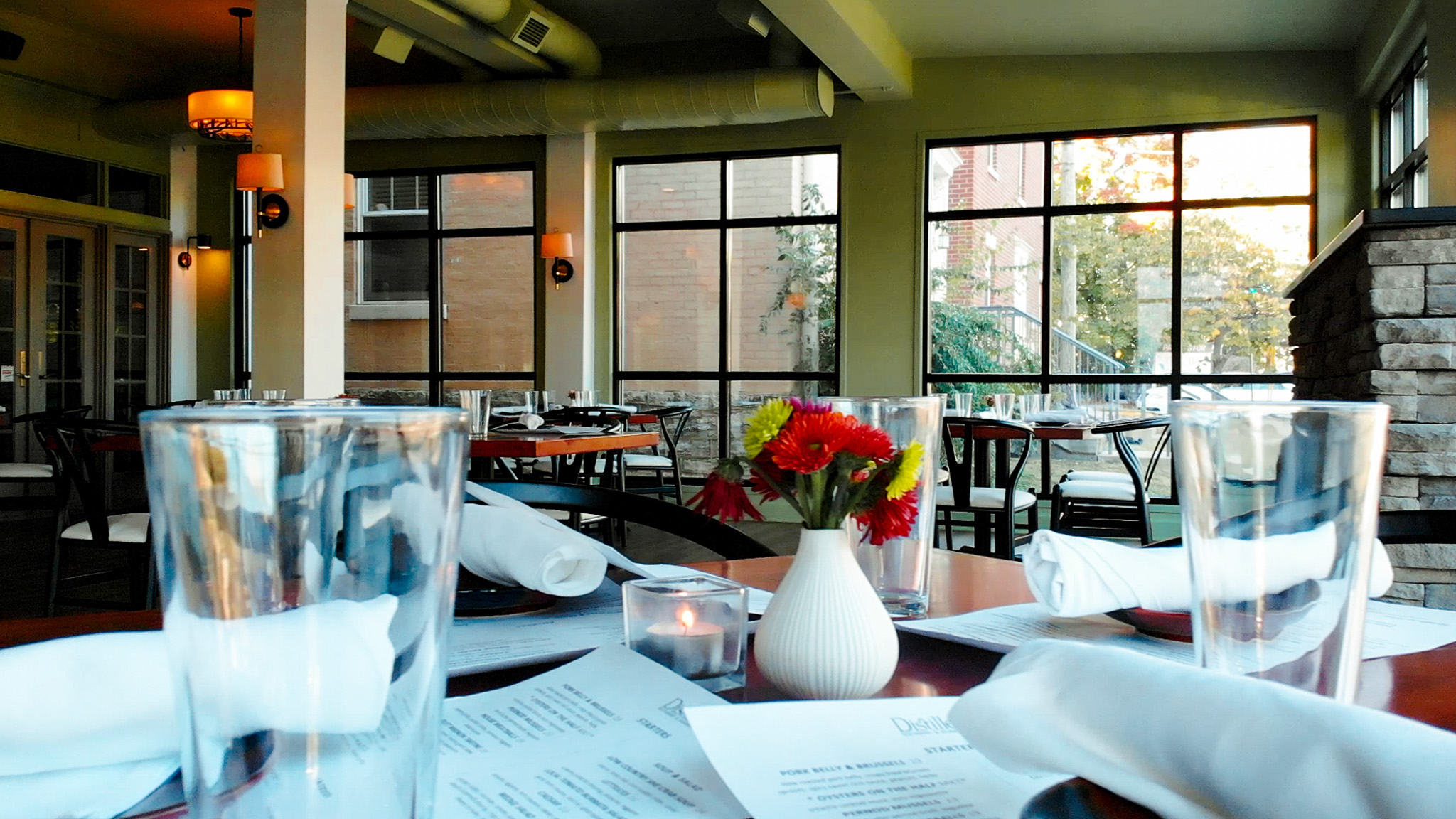 Elegant dining tables set with glassware and fresh flowers in a beautifully lit restaurant