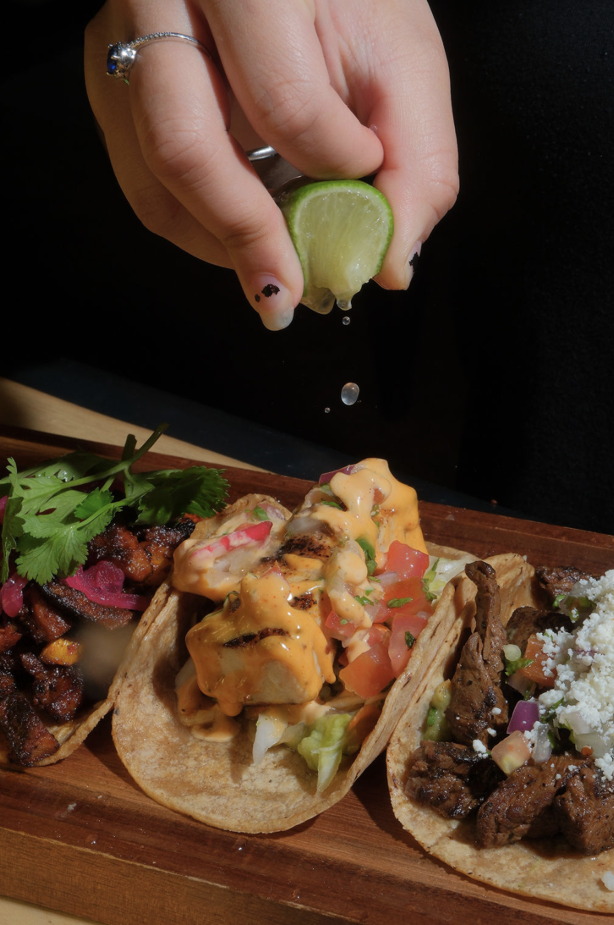 Lime getting squeezed on top of a fish taco