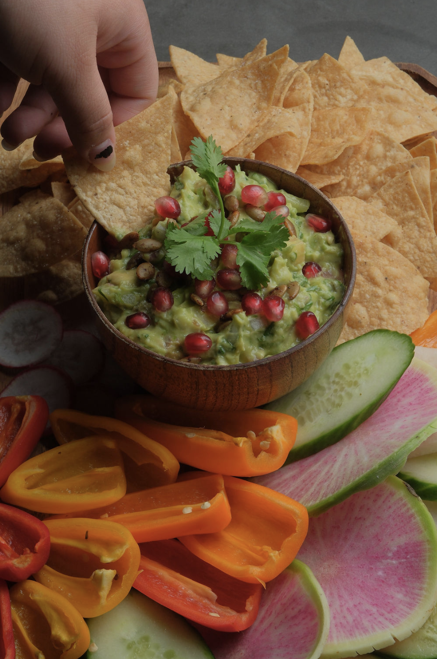 Hand dipping a chip into guacamole