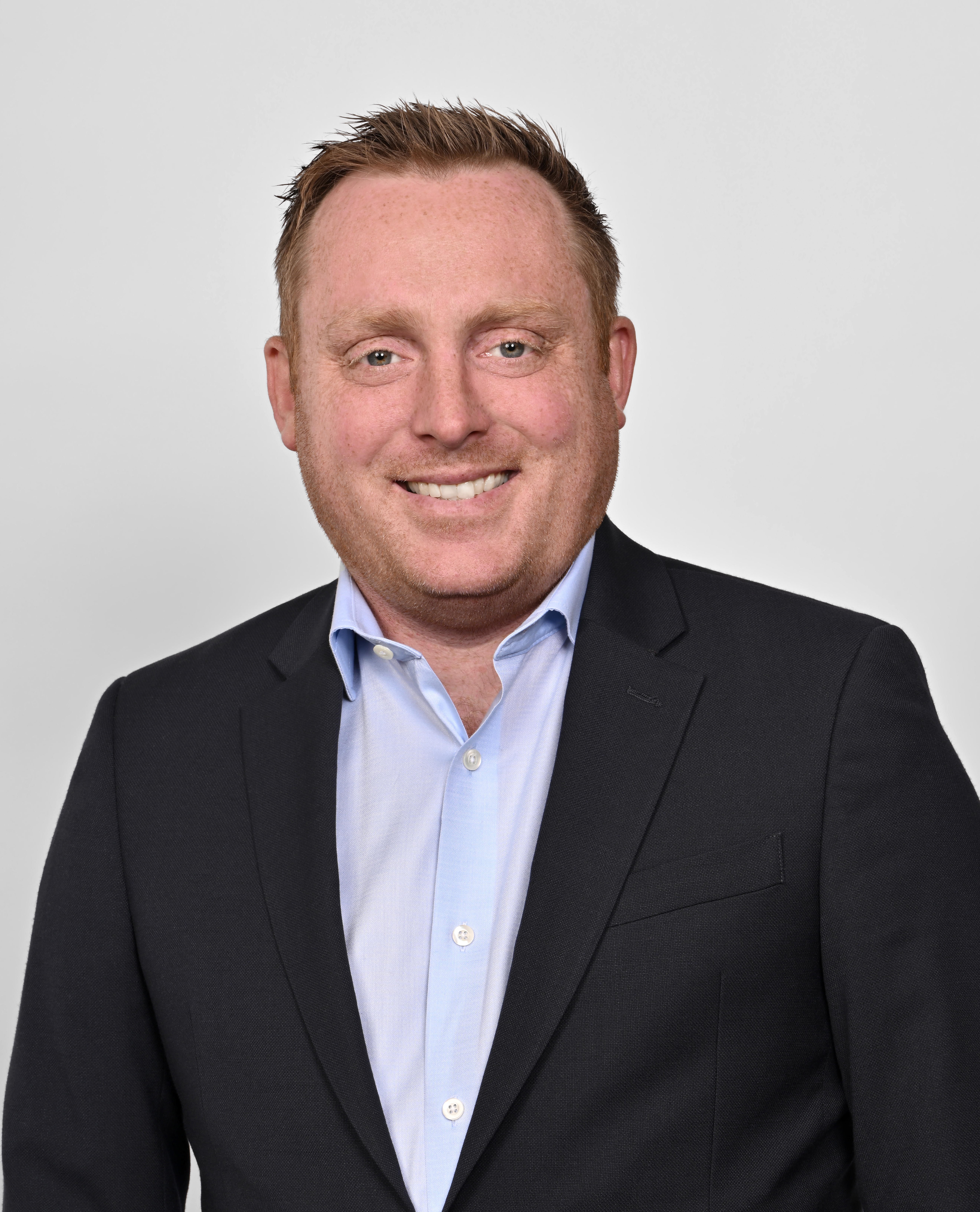 a man wearing a suit and tie smiling at the camera