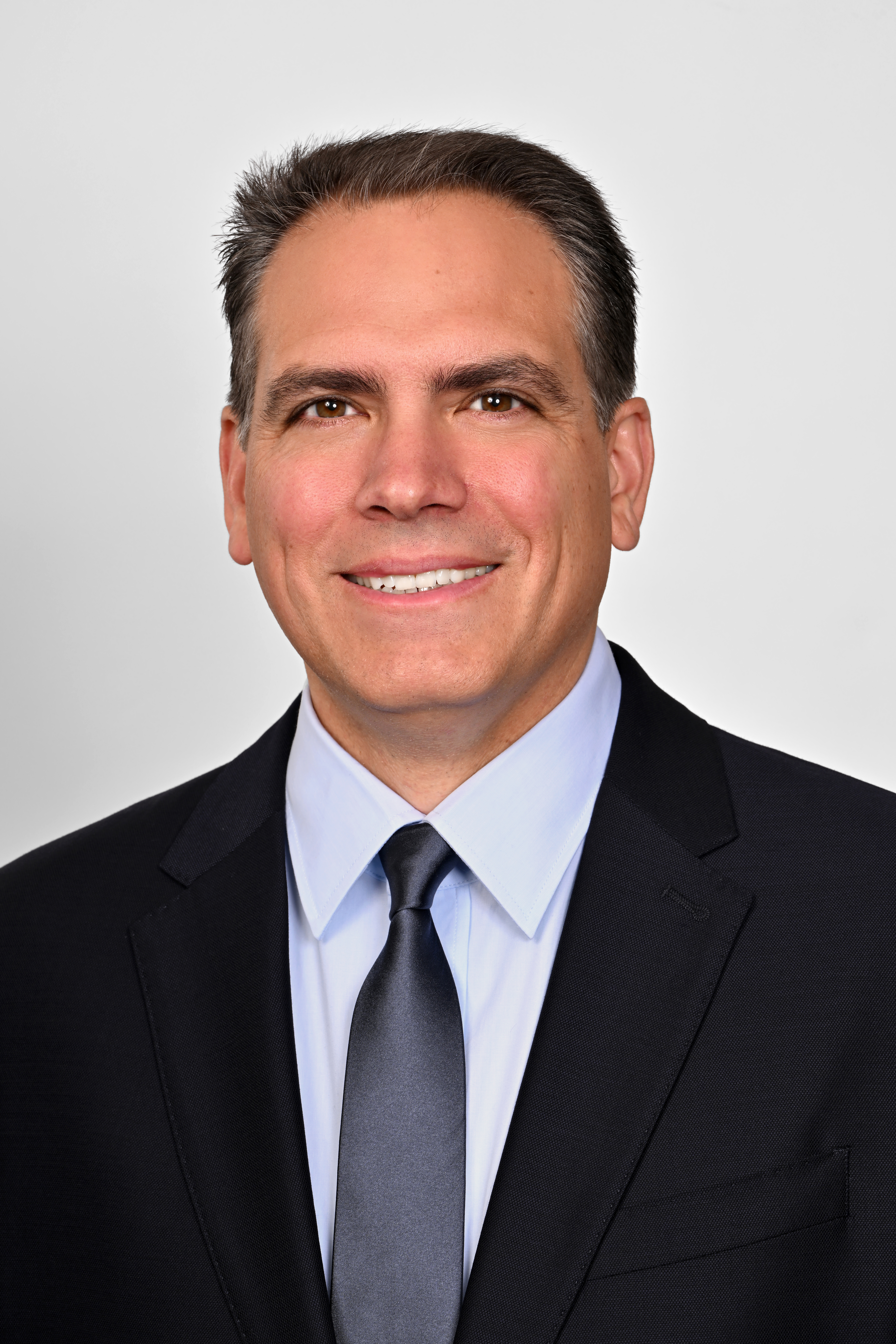 a man wearing a suit and tie smiling at the camera