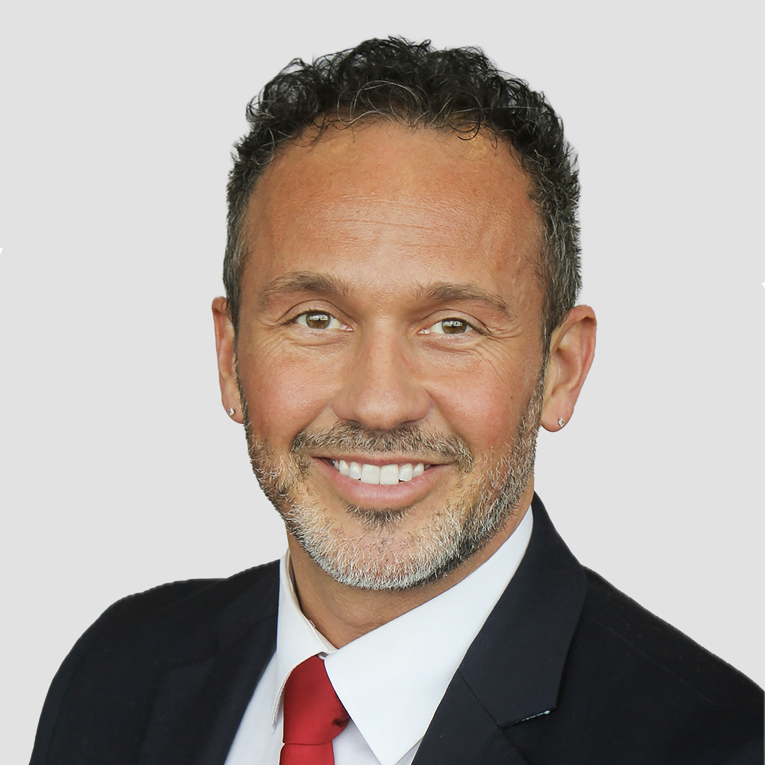 a man wearing a suit and tie smiling and looking at the camera
