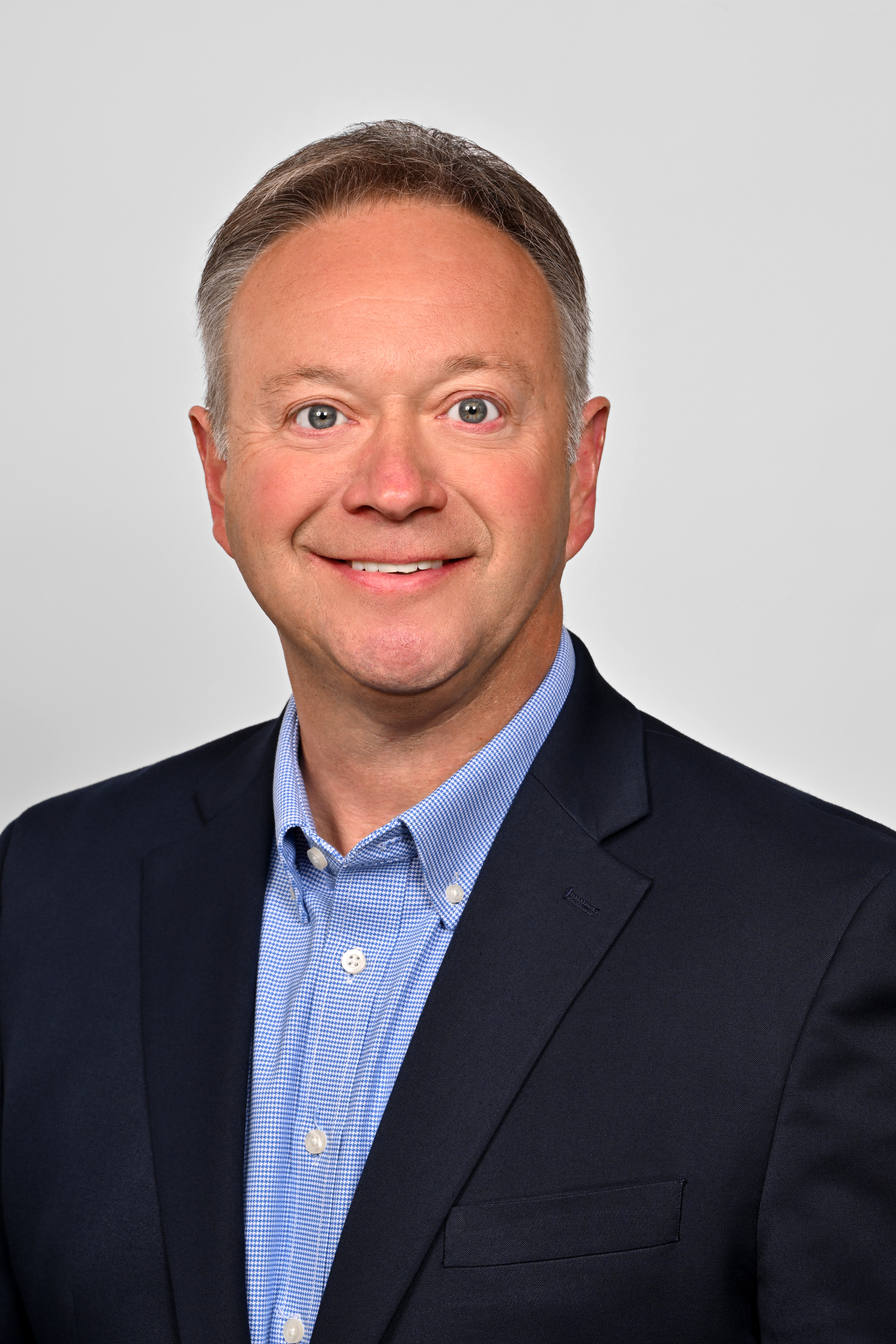 a man wearing a suit and tie smiling and looking at the camera