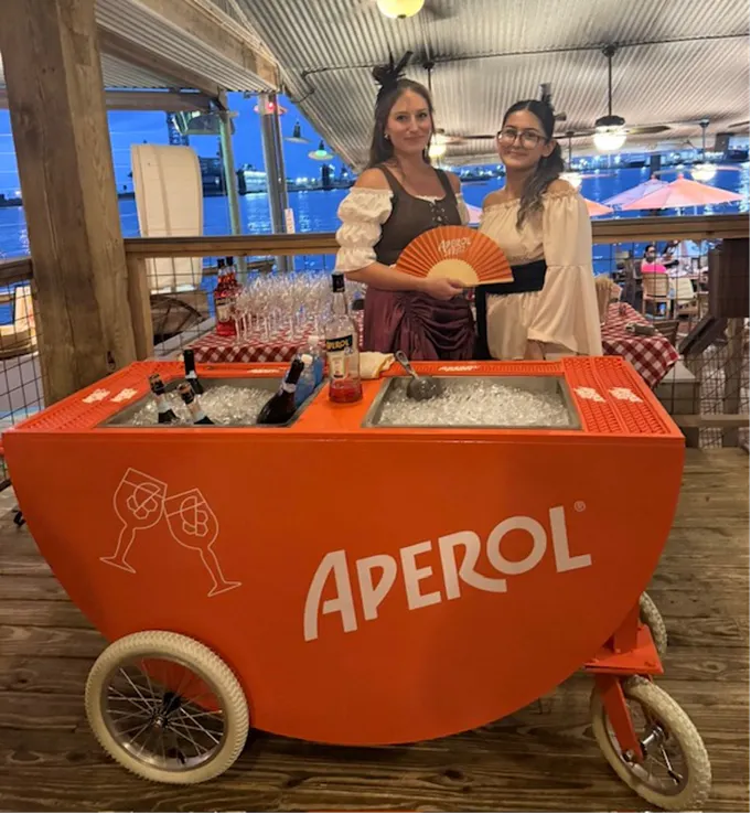 two women standing next to a cooler