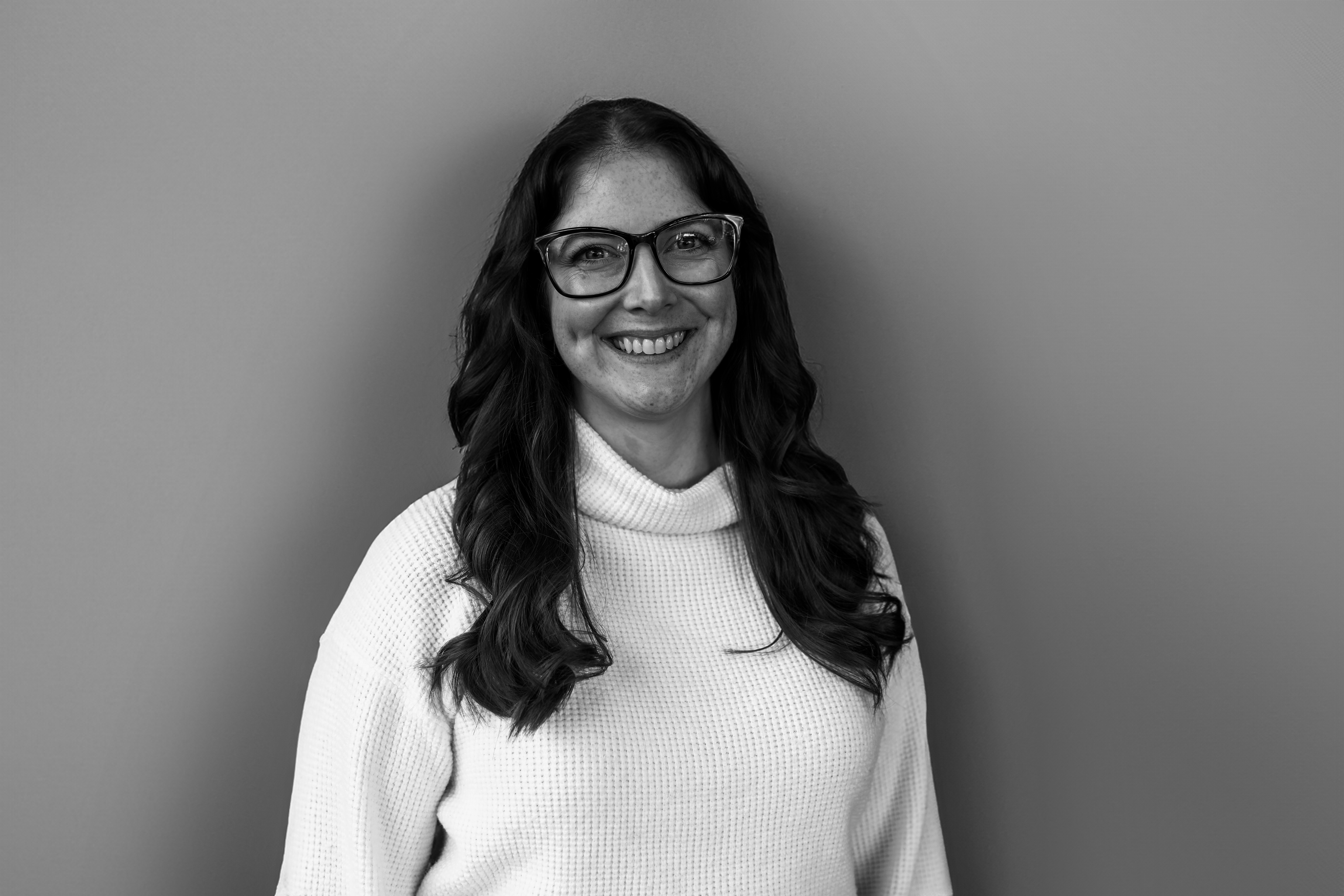 a woman wearing glasses and smiling at the camera
