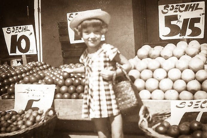 a person standing in front of a store filled with lots of fruit