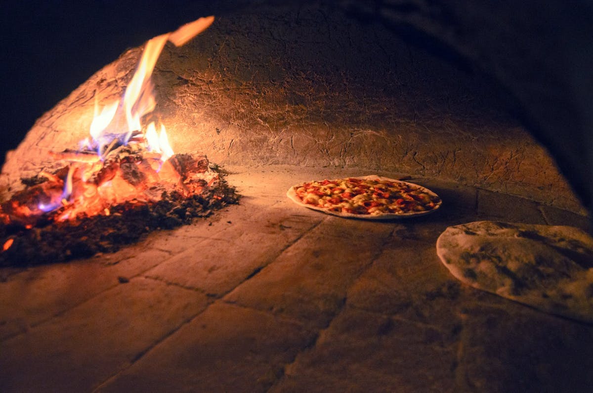 a pizza sitting on top of a fire oven