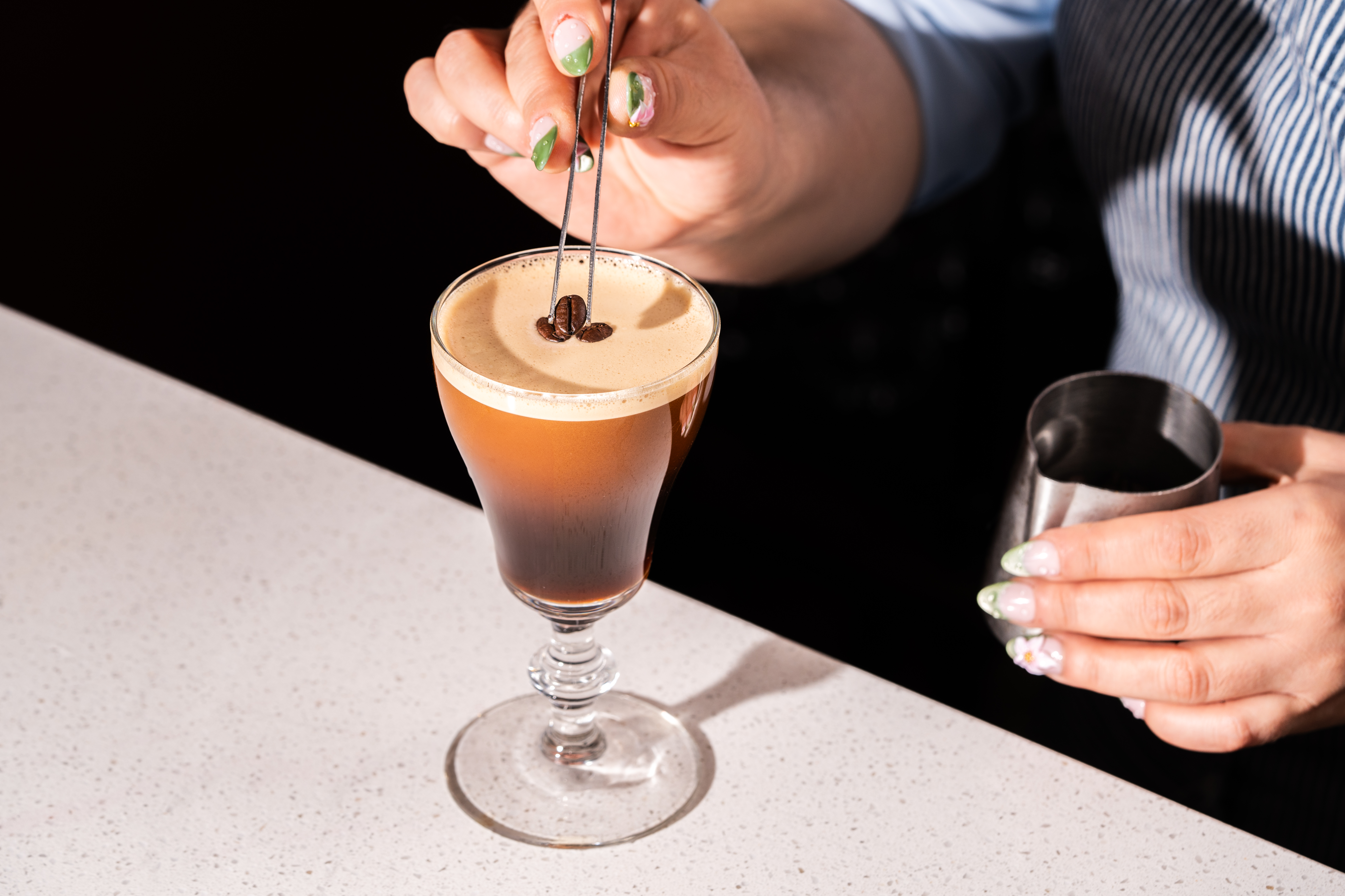 a person stirring a drink with a coffee bean in it