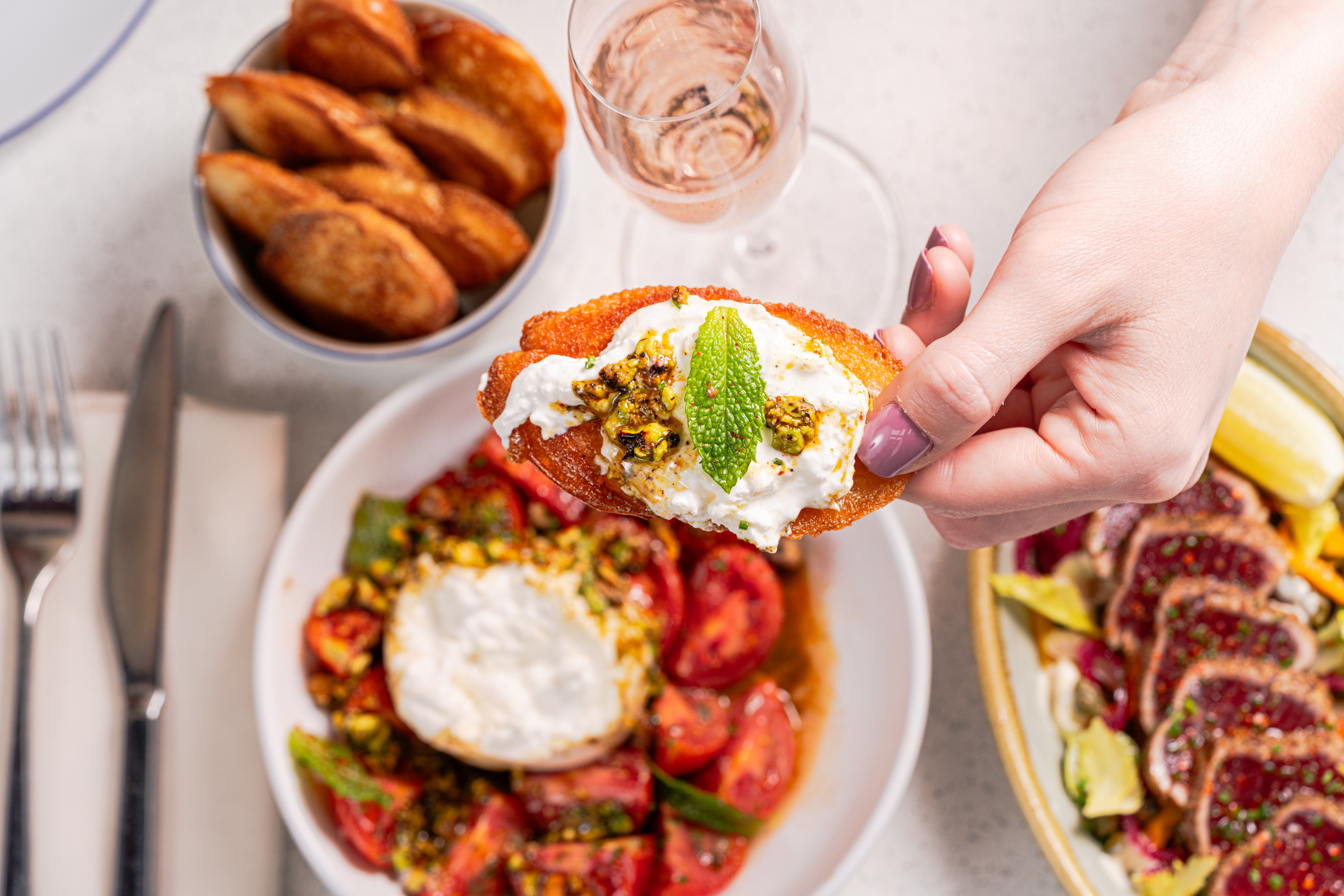 a hand holding a piece of bread with a white cream cheese topping