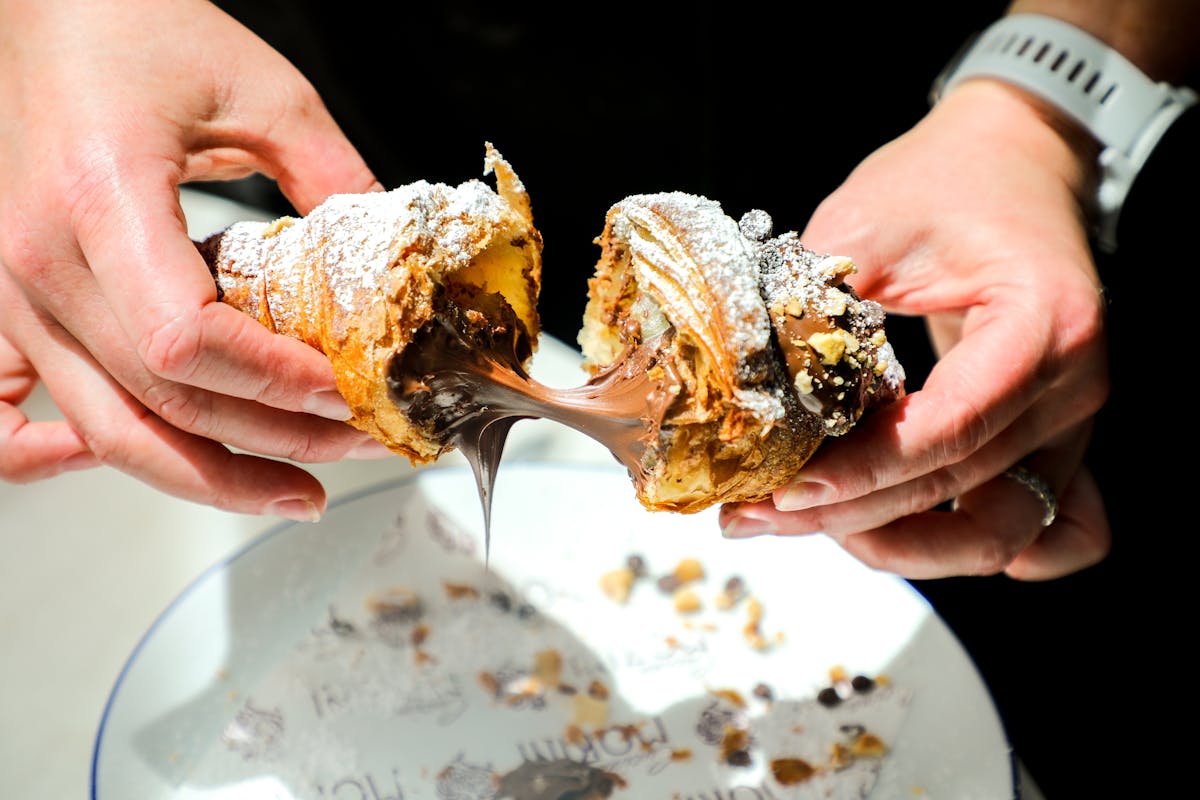 a hand holding a piece of food on a plate