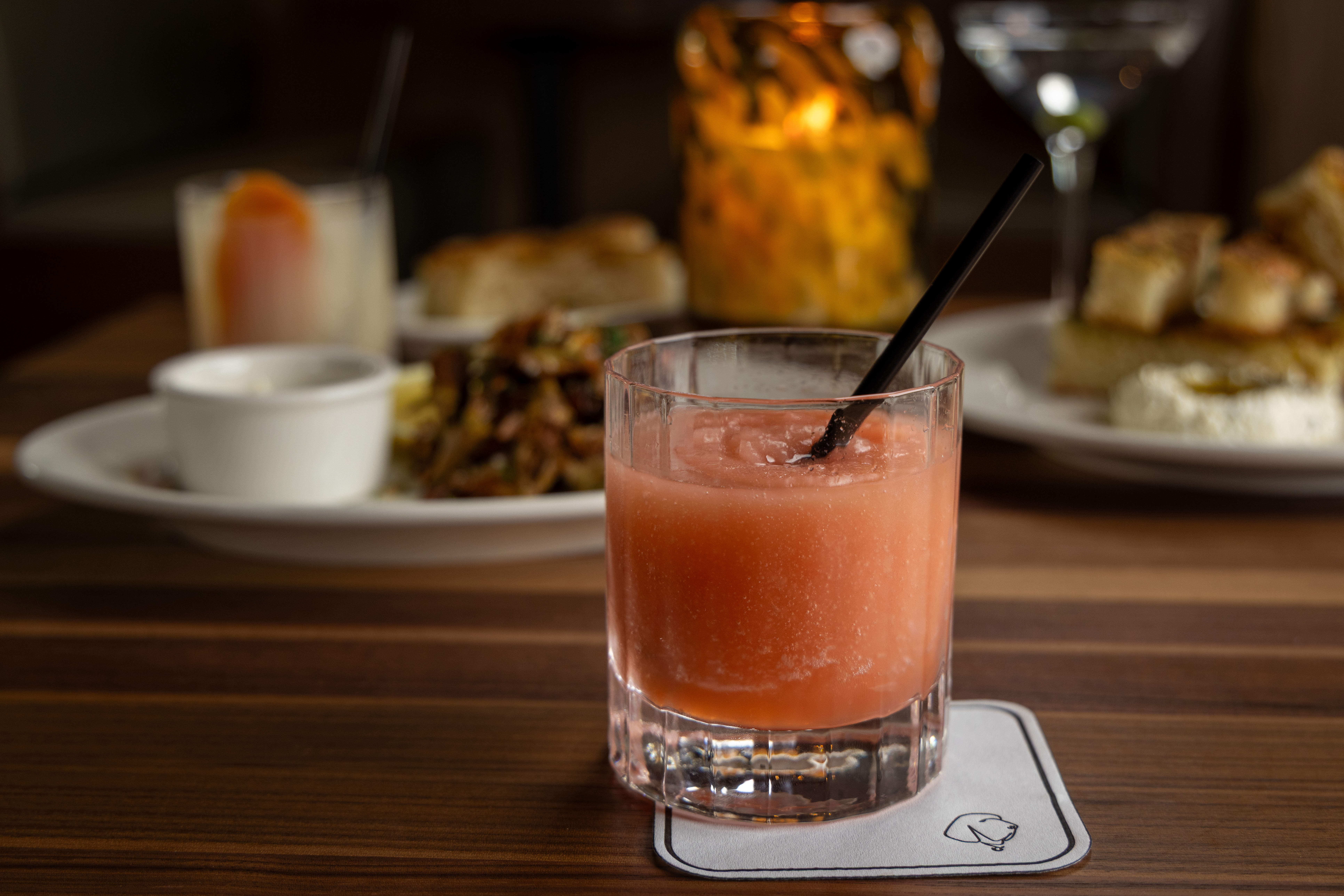 a glass of pink liquid with a black straw