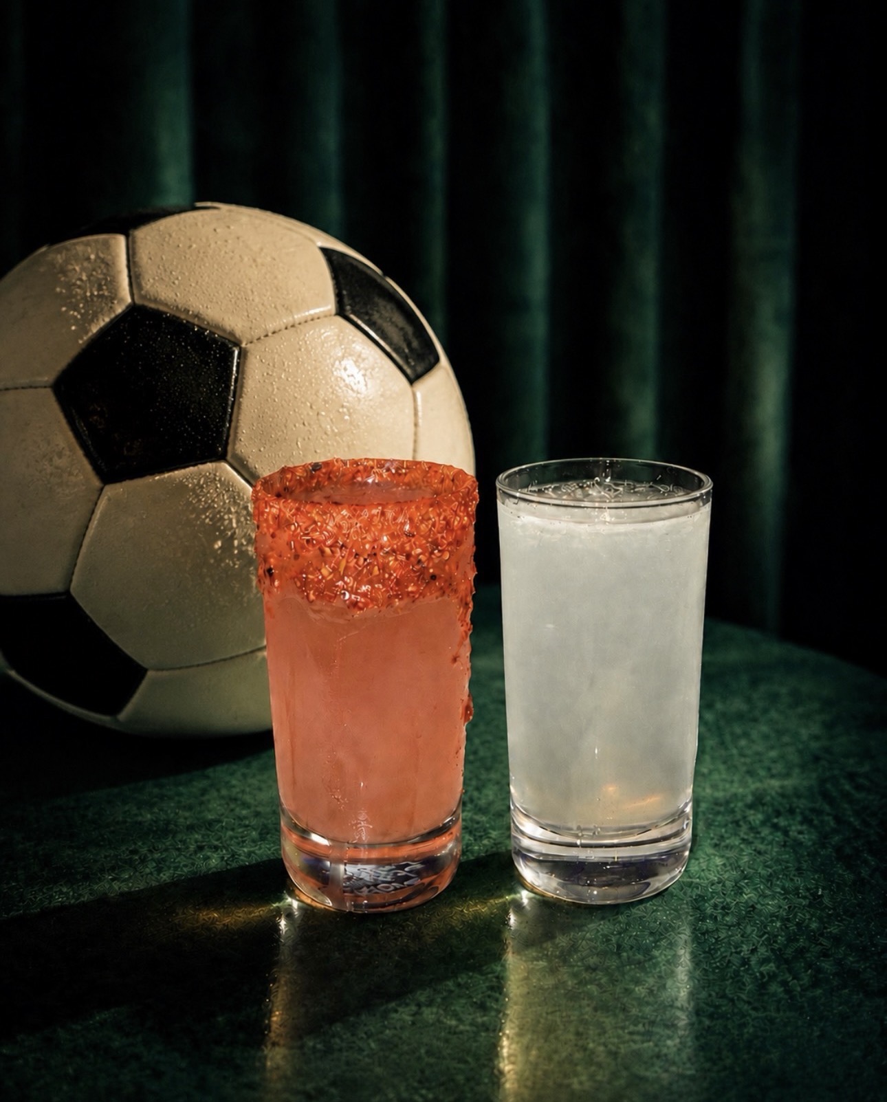 a glass of liquid next to a football ball