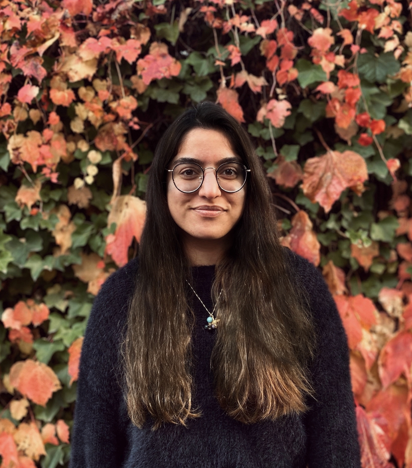 a woman in front of a wall of leaves