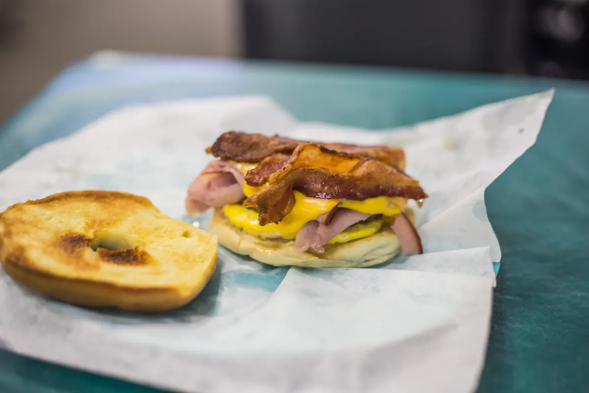 The Maltese Falcon: buttered and toasted breakfast bagel, scrambled egg, American cheese with ham, bacon, and sausage