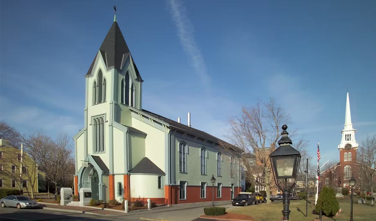 a church with a clock on the side of a road