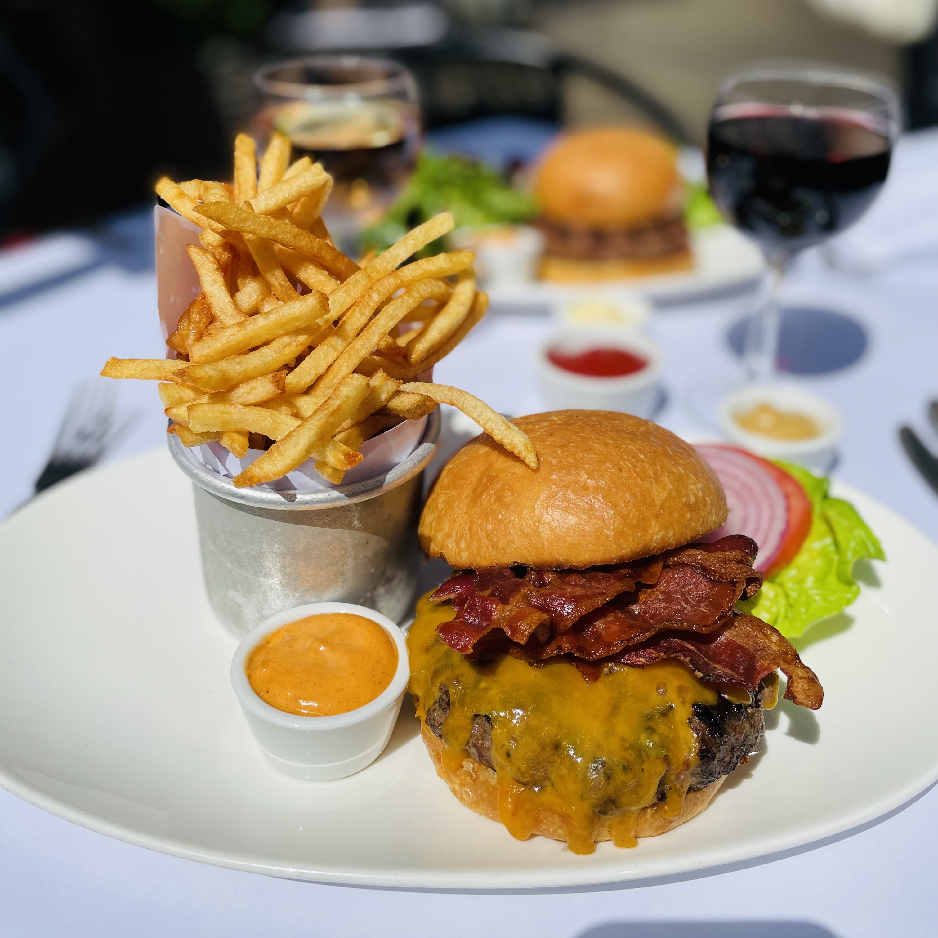 Juicy cheddar cheese burger with chipotle mayonnaise and crispy French fries and a glass of red wine