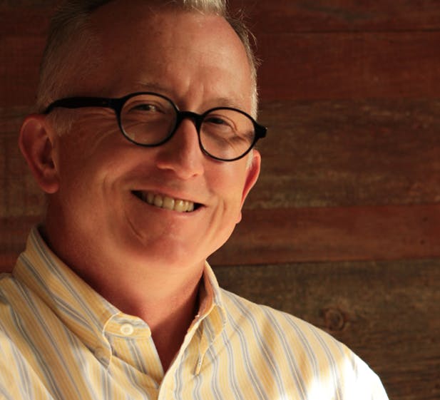 a man wearing glasses and smiling at the camera