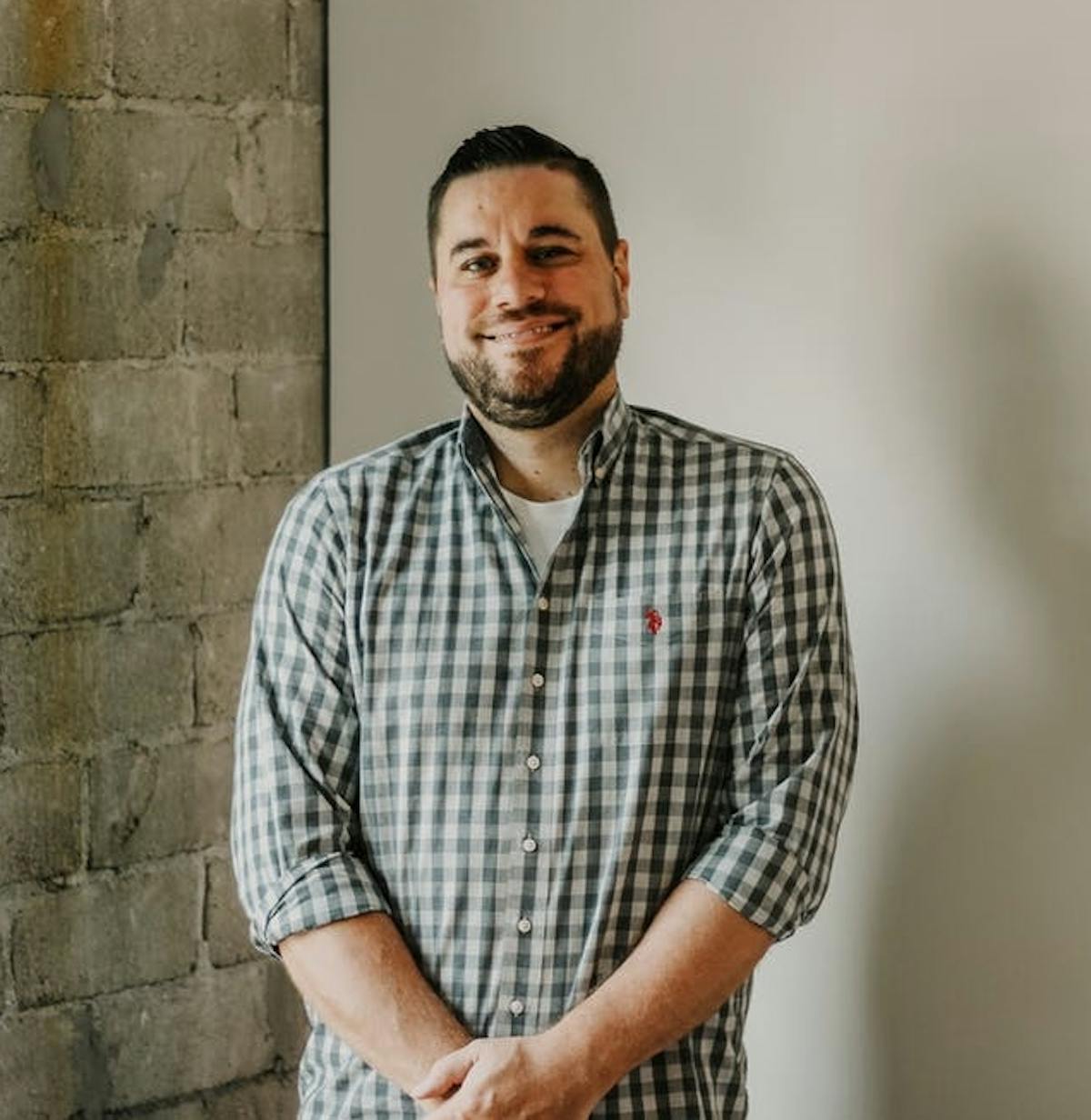 a man standing in front of a brick wall