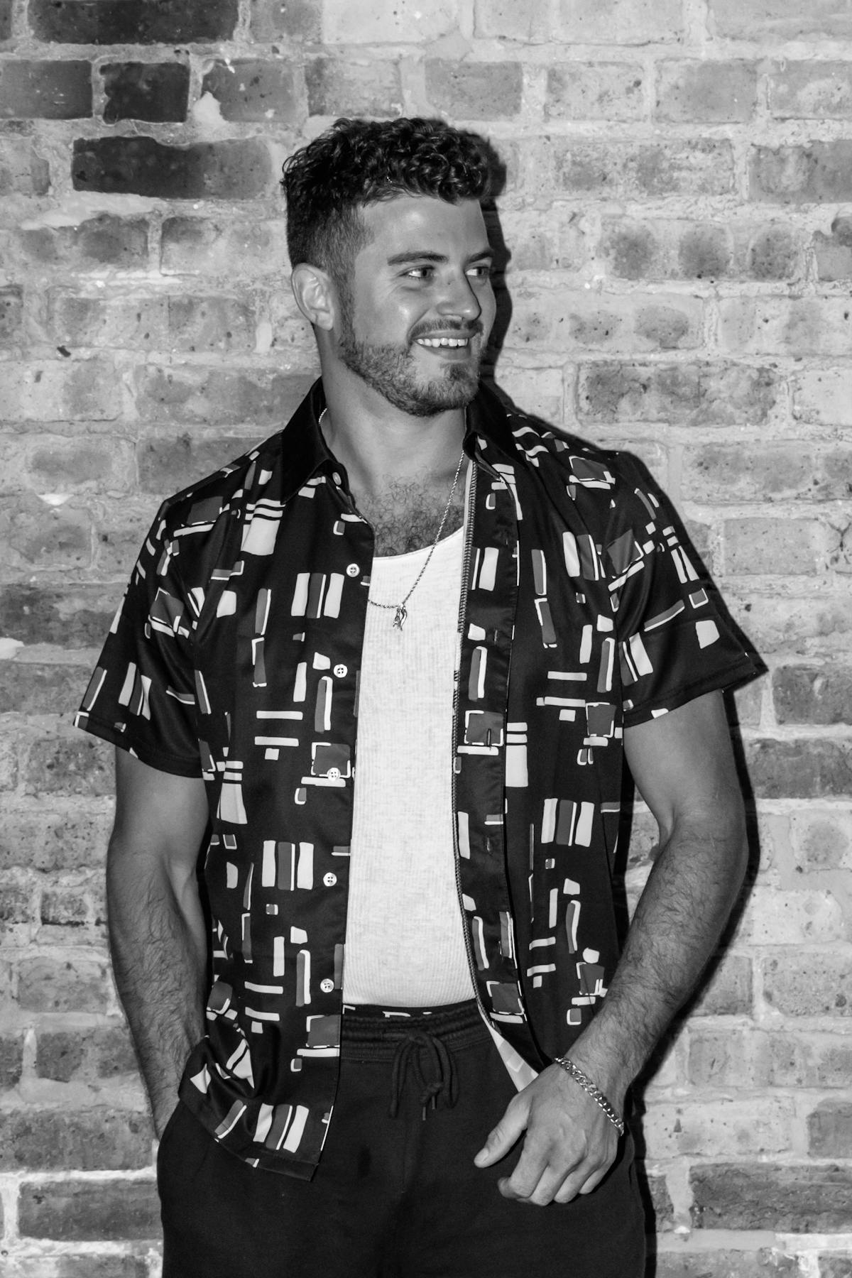 a man standing next to a brick wall