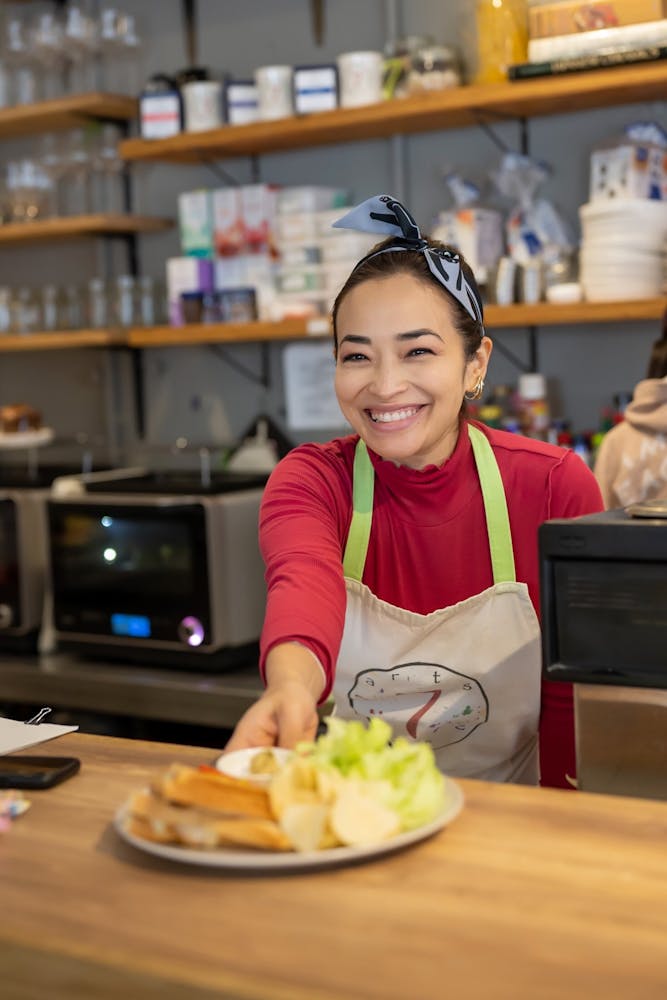 a person sitting at a table with a laptop and smiling at the camera