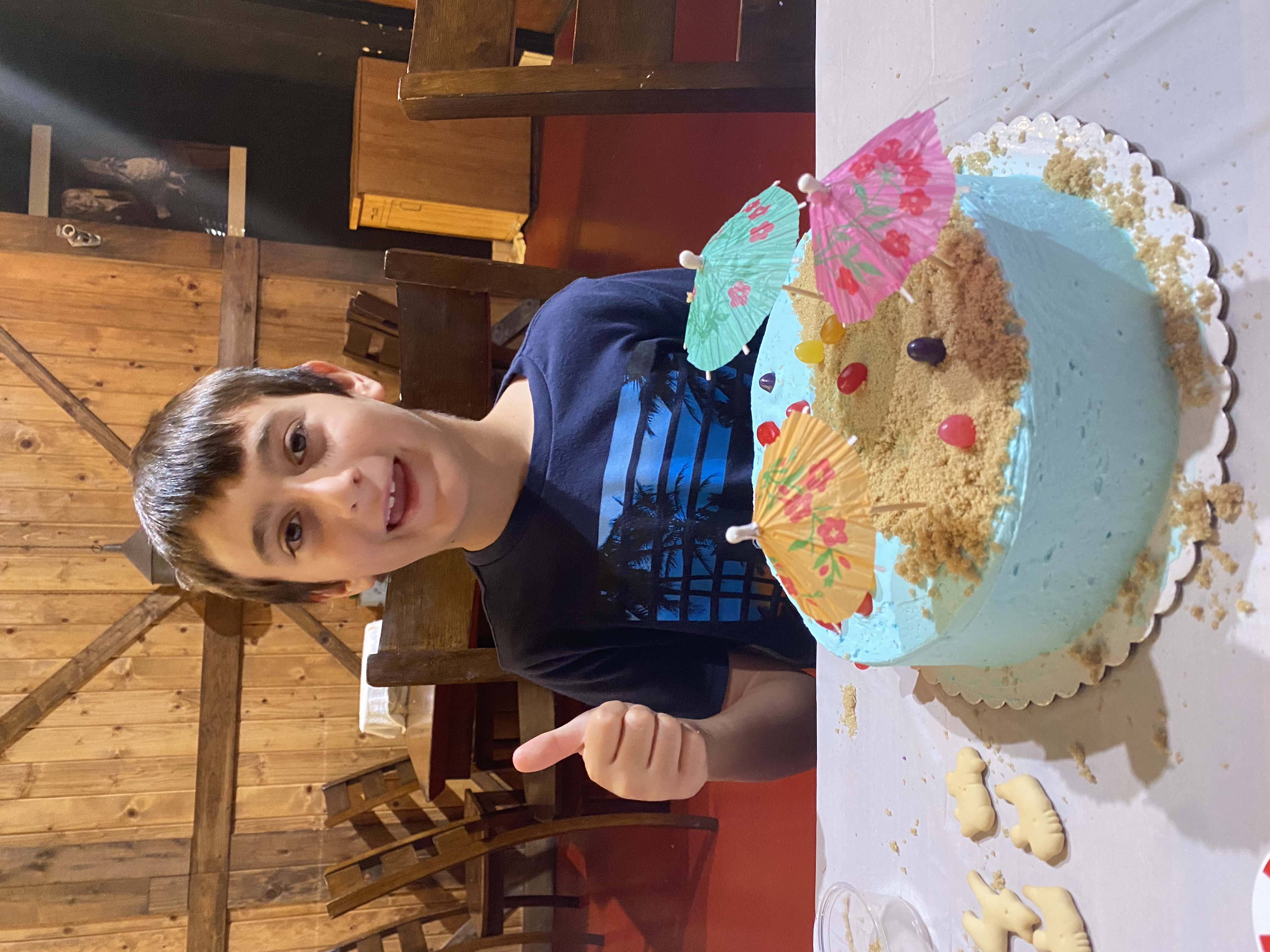 a boy sitting at a table with a birthday cake