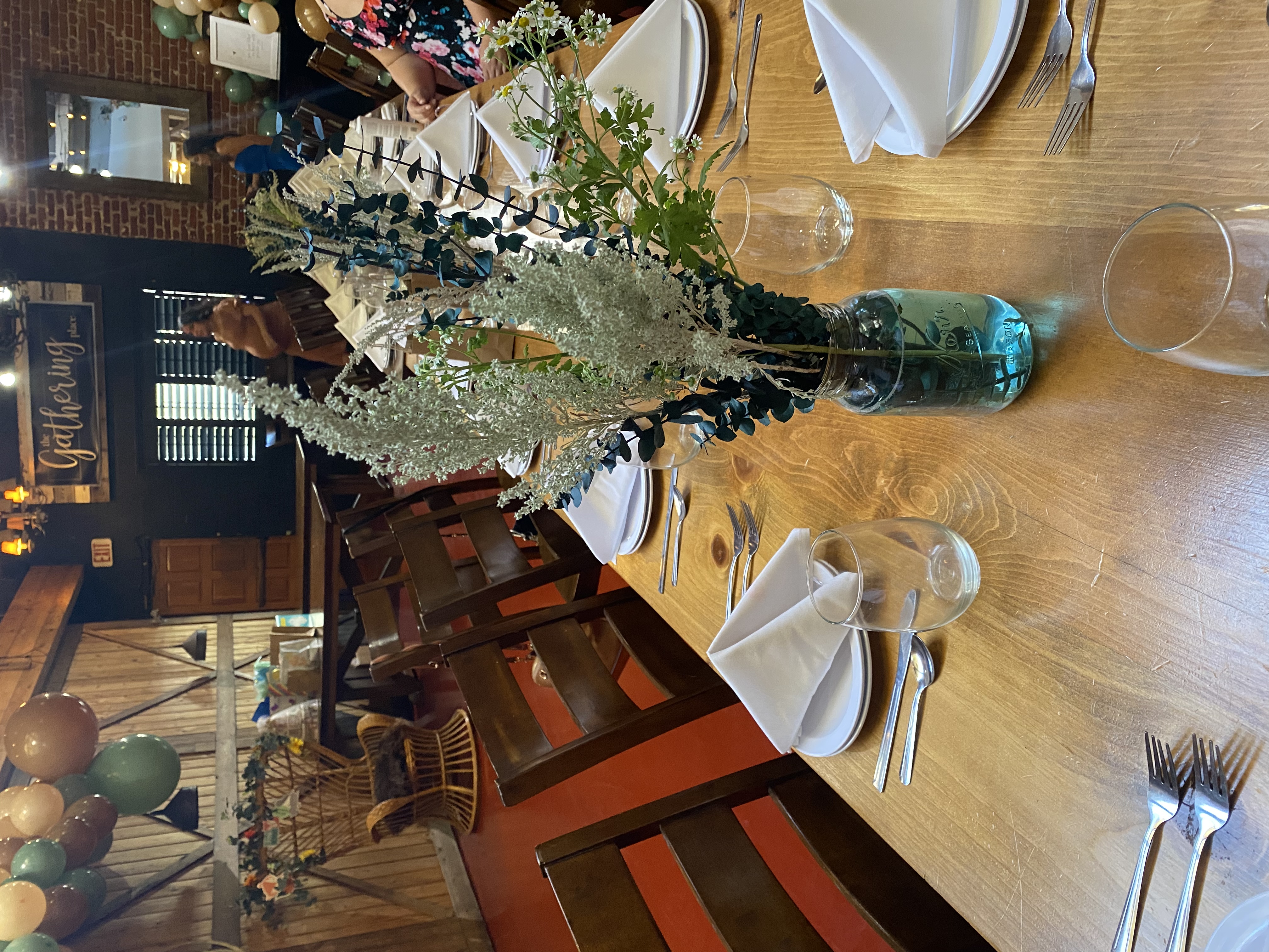 a group of people sitting at a table with a vase of flowers