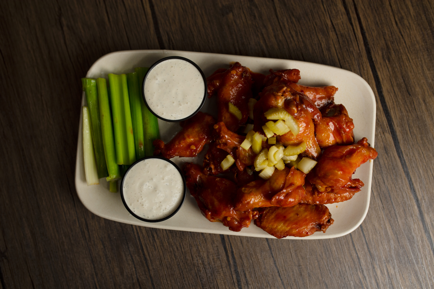 Chicken wings a plate of food sitting on top of a wooden table