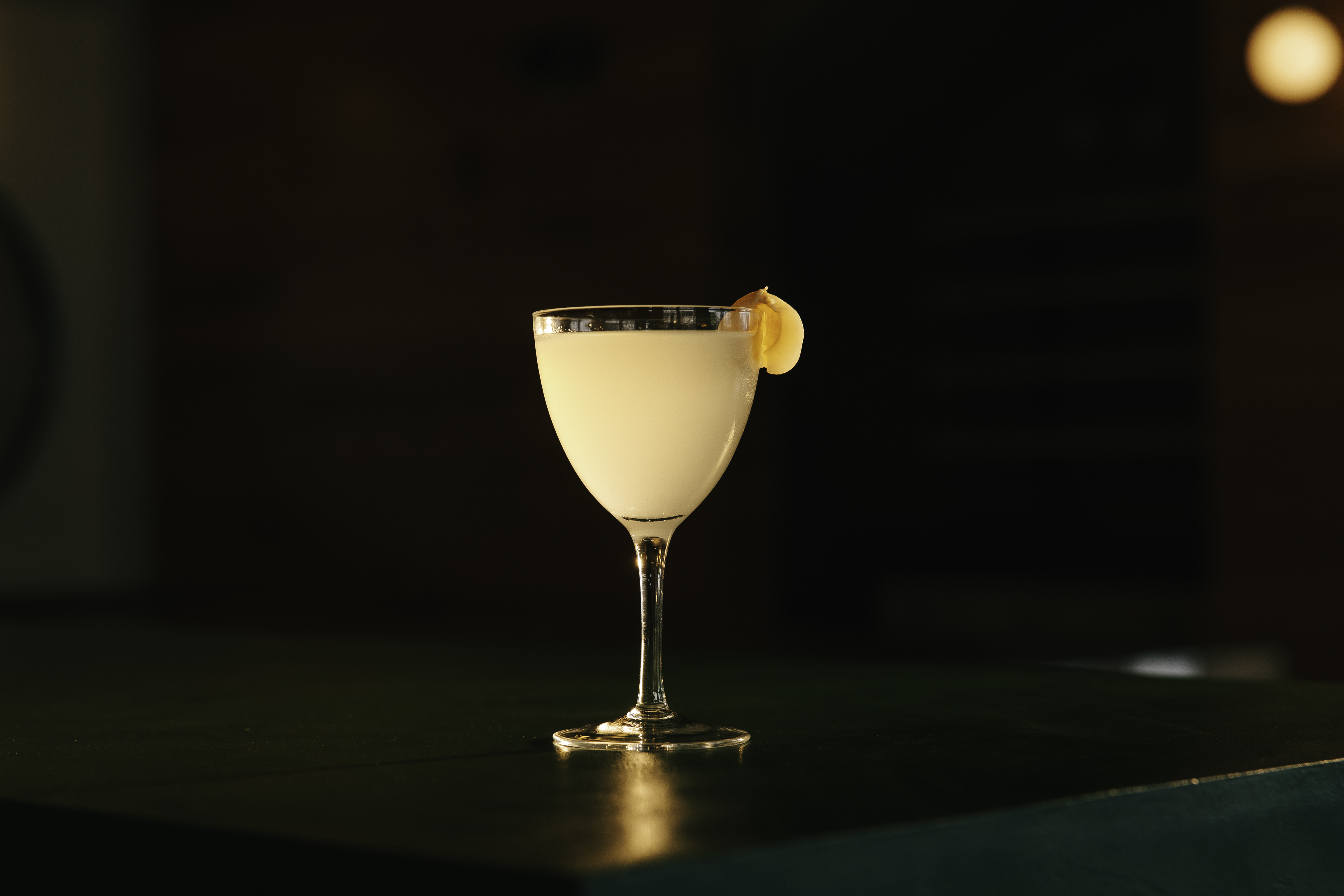 a glass of liquid with a slice of orange on top of it