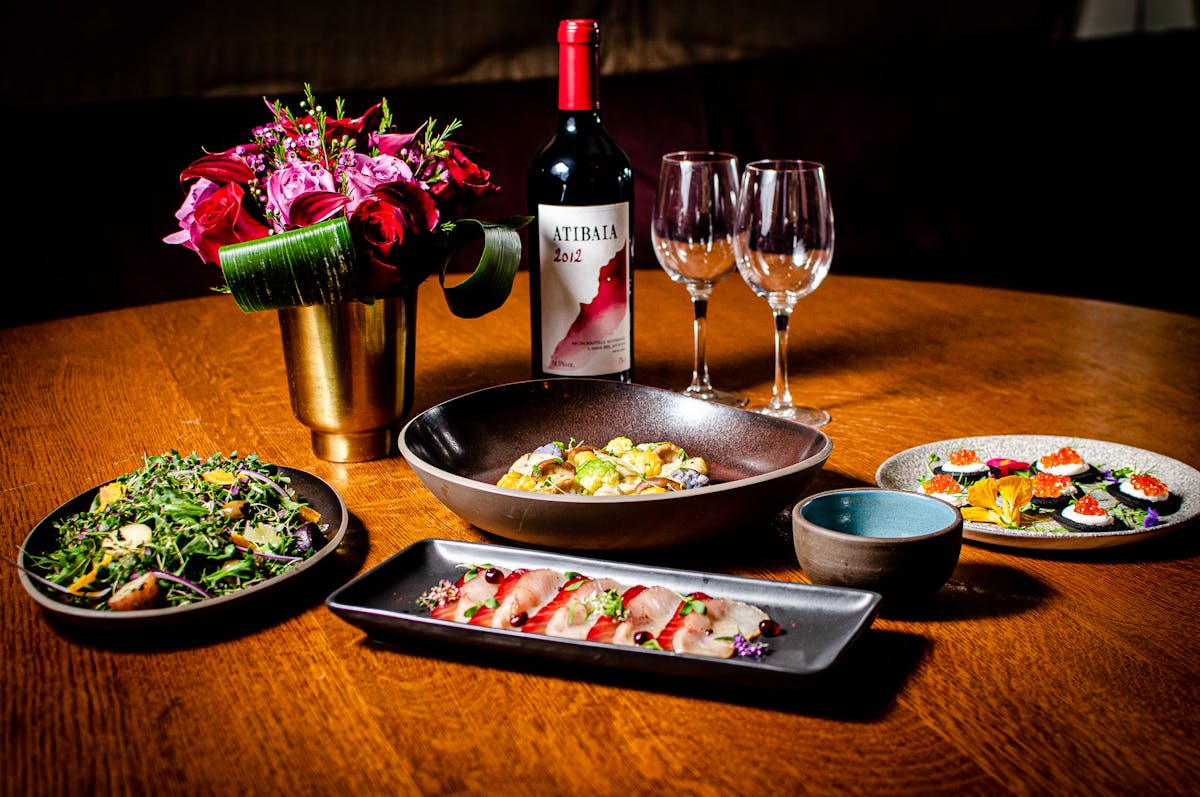 a table topped with plates of food and a glass of wine