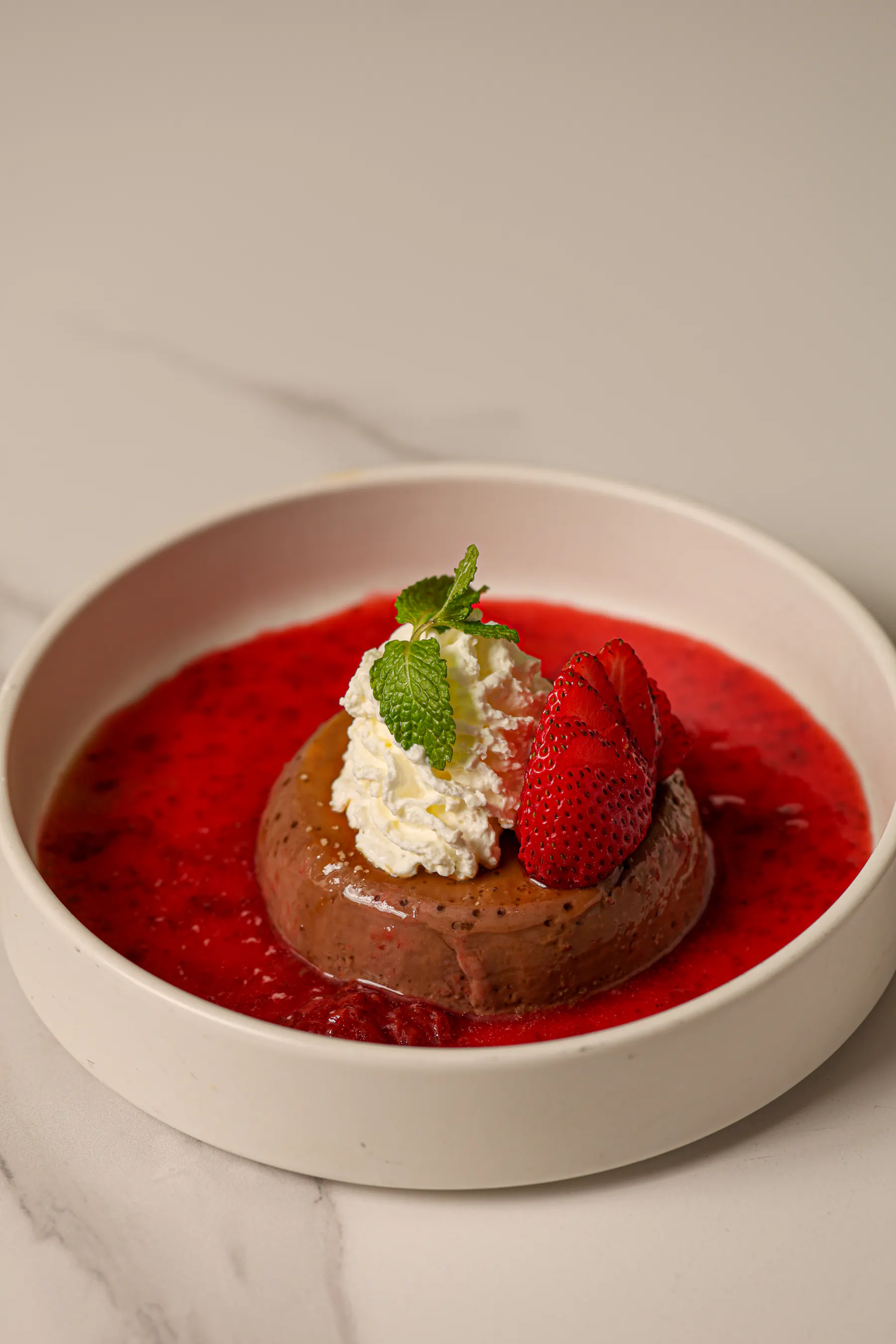 a bowl of dessert with strawberries and whipped cream