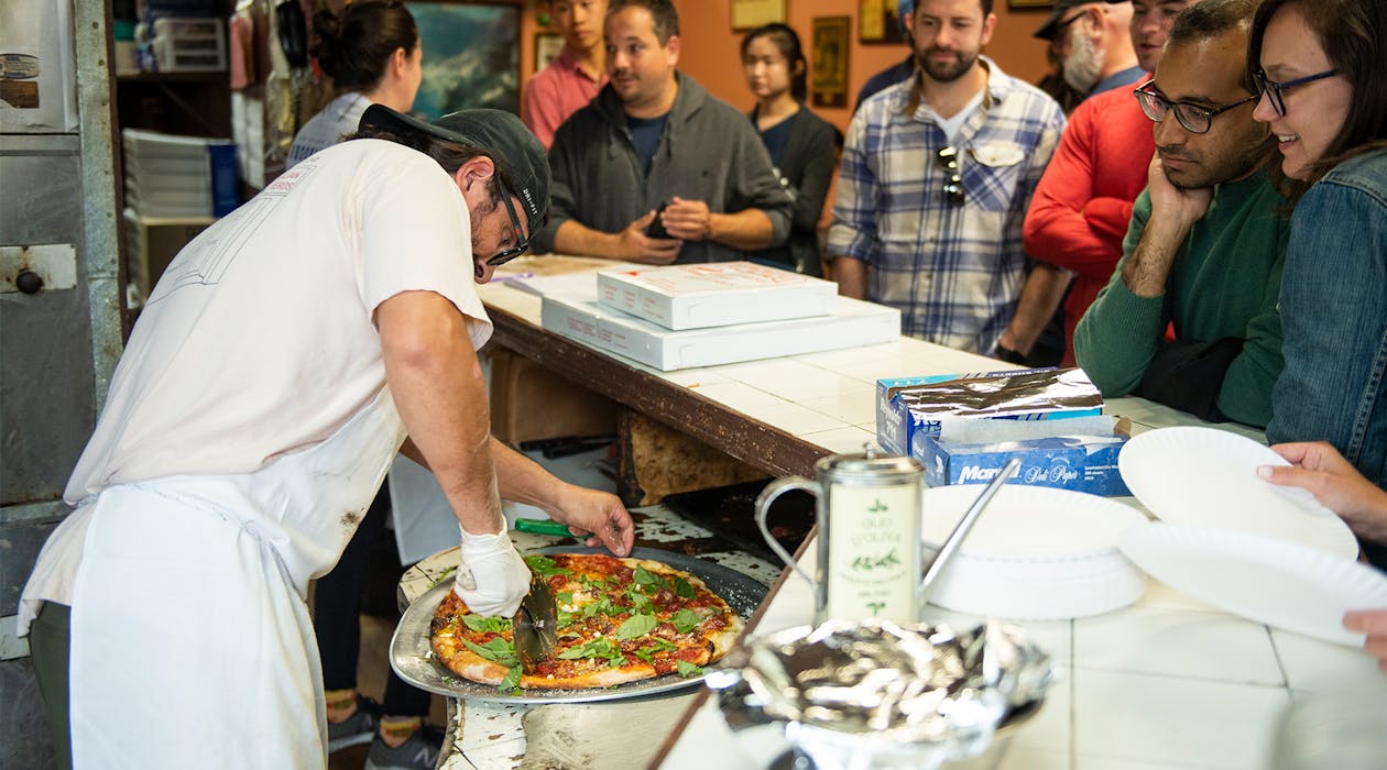 A group of people watching a pizza being prepared