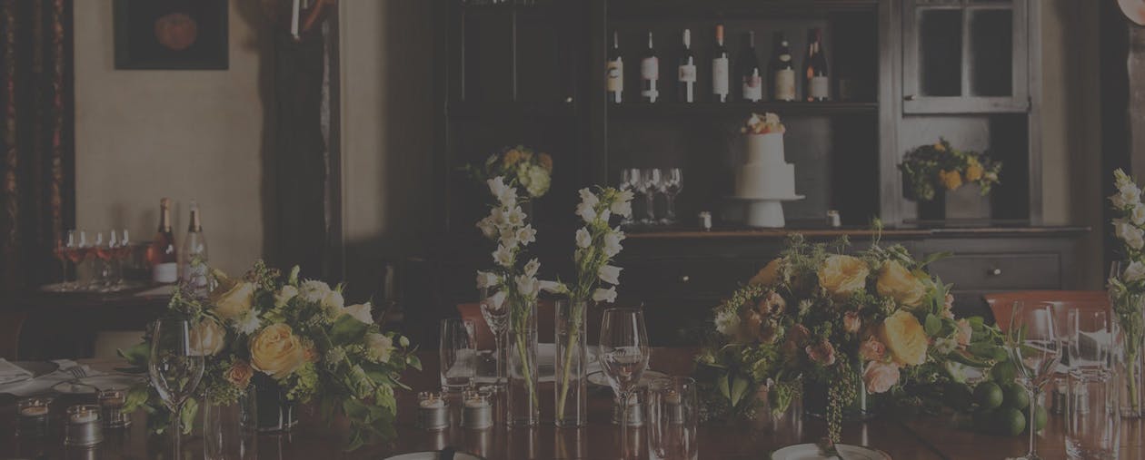 a vase of flowers on a table with wine glasses