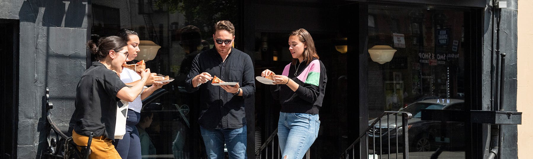 group of people eating outside of a pizza restaurant