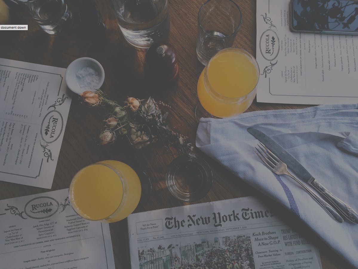 Restaurant menus, drinks and a newspaper on a table.