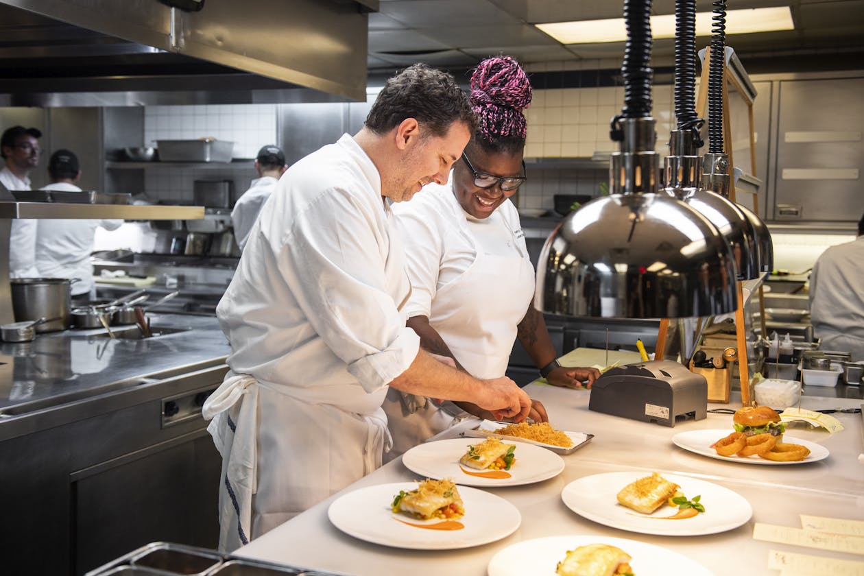 chef assisting cook with preparing dishes