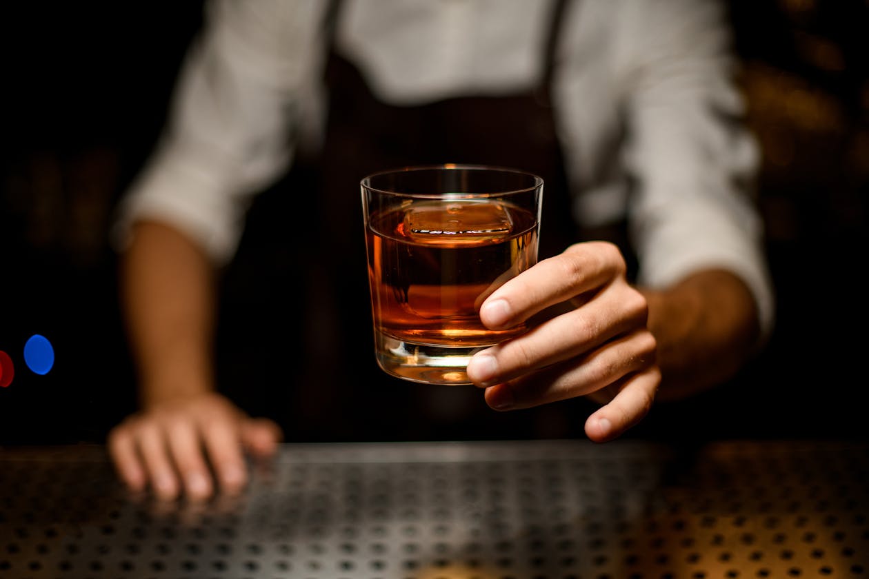 a hand holding a glass of whiskey