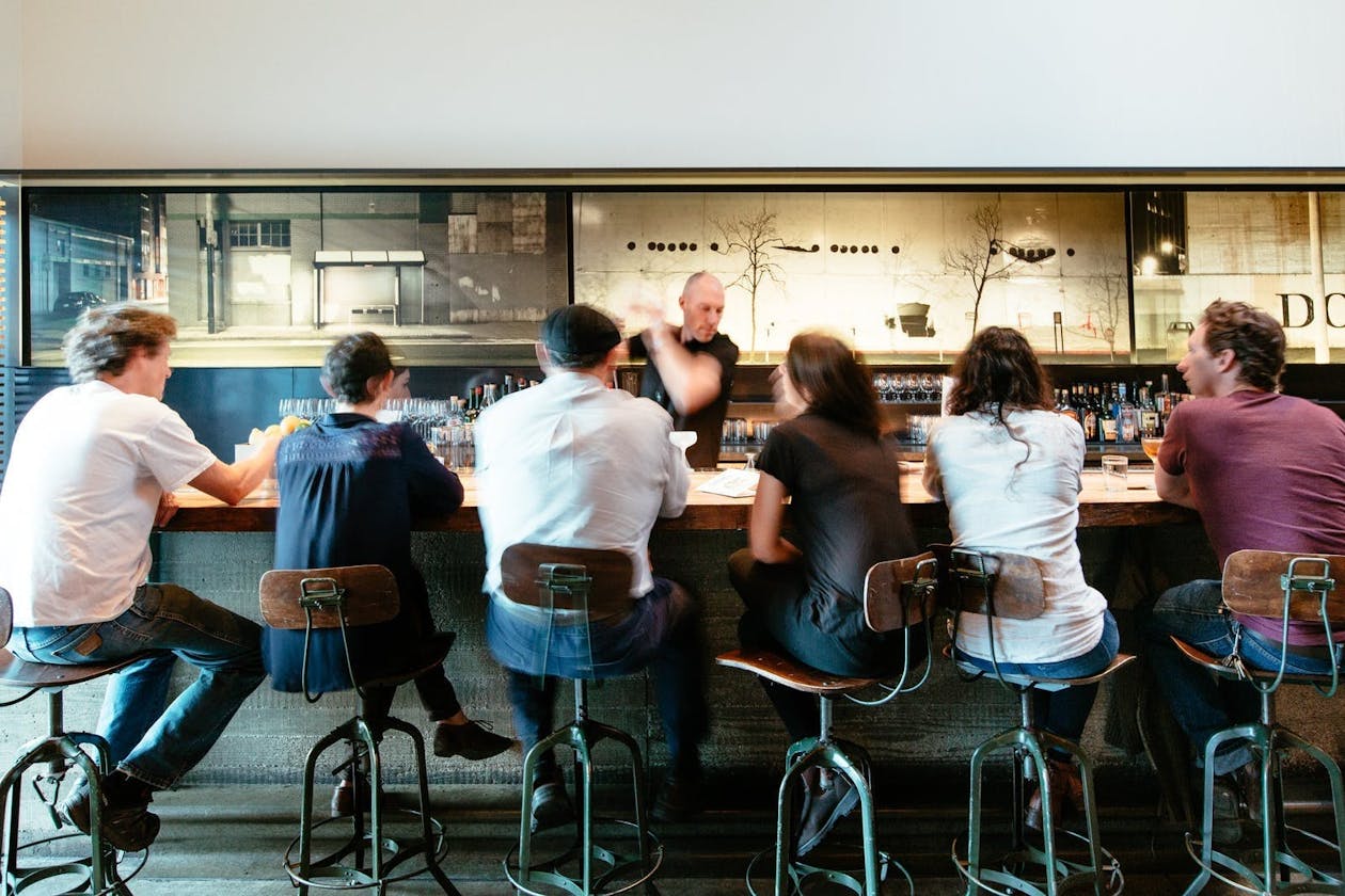 Bar Agricole's bartender serving guests drinks at the main interior bar.