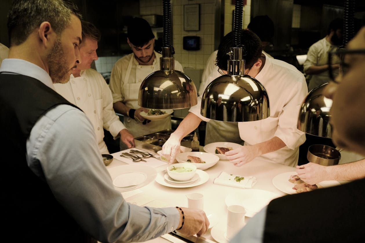 a group of people standing at a table prepping plates for service