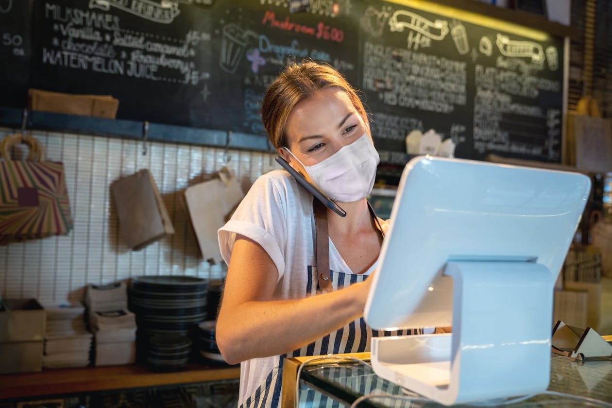 A restaurant owner on the phone and using a POS