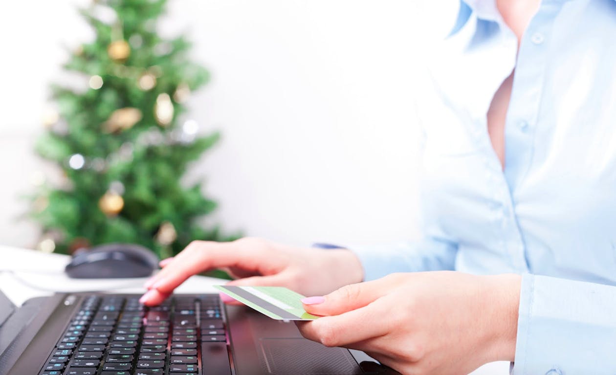a person using a laptop with a credit card in their hand