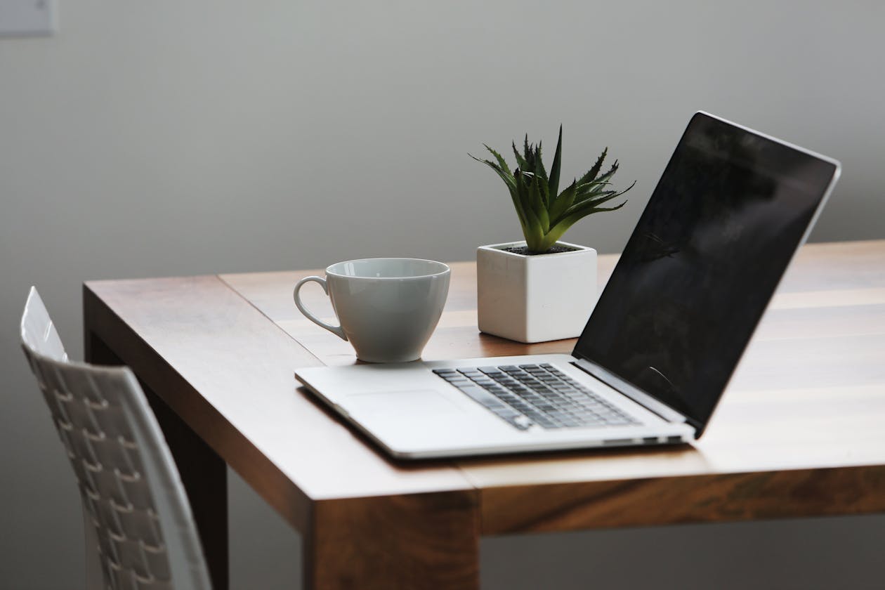 a desk with a laptop computer sitting on top of a wooden table