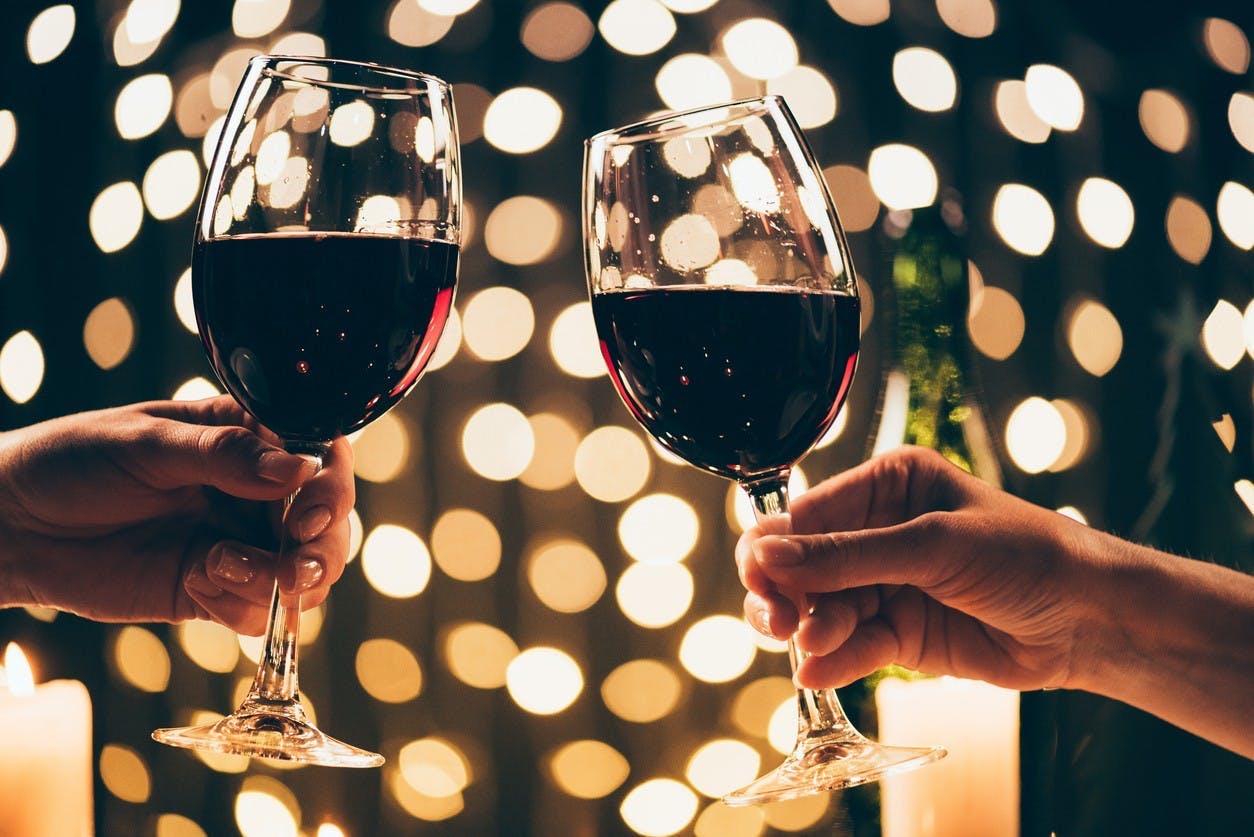 two people cheersing glasses of red wine