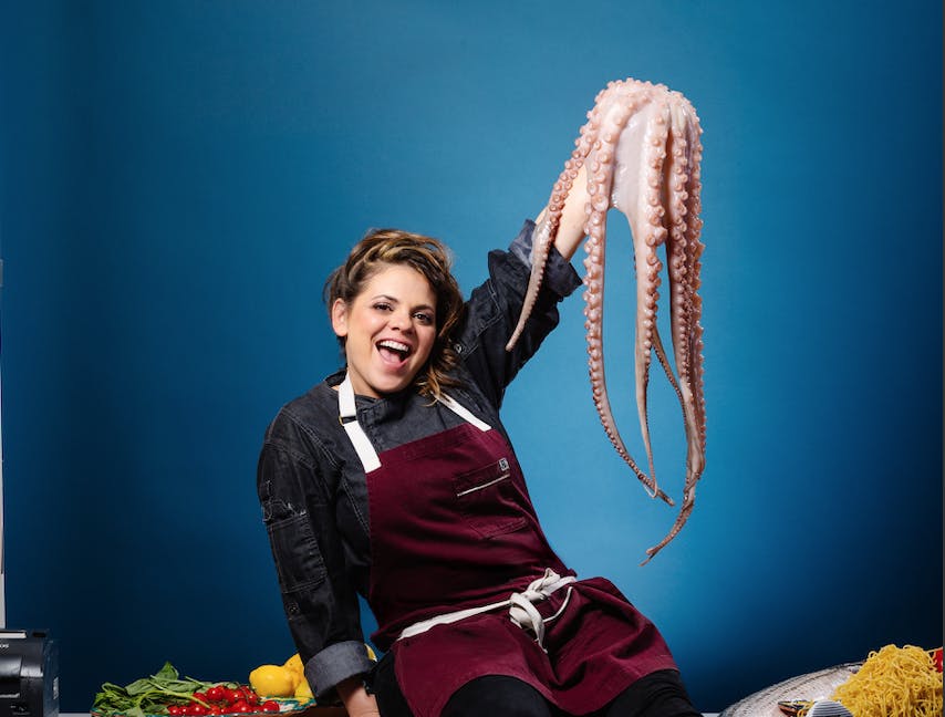 a person posing for the camera with an octopus in hand.
