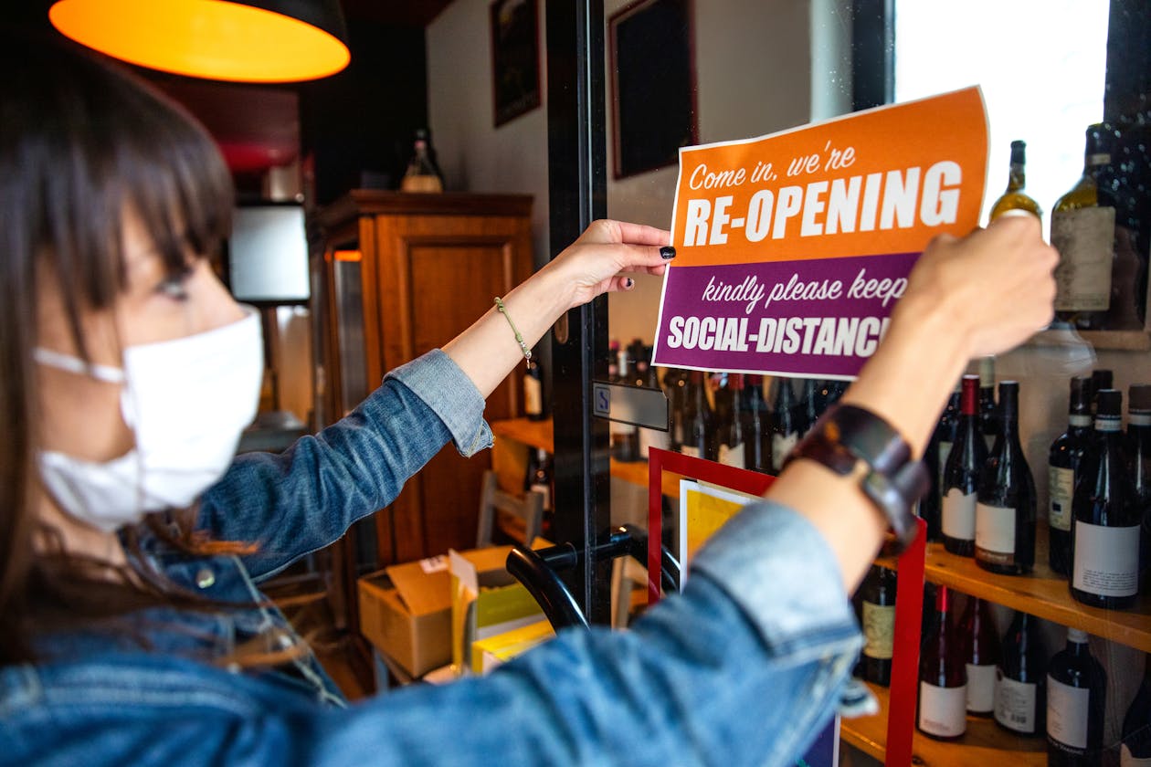 A restaurant owner puts up a reopening sign - COVID-19