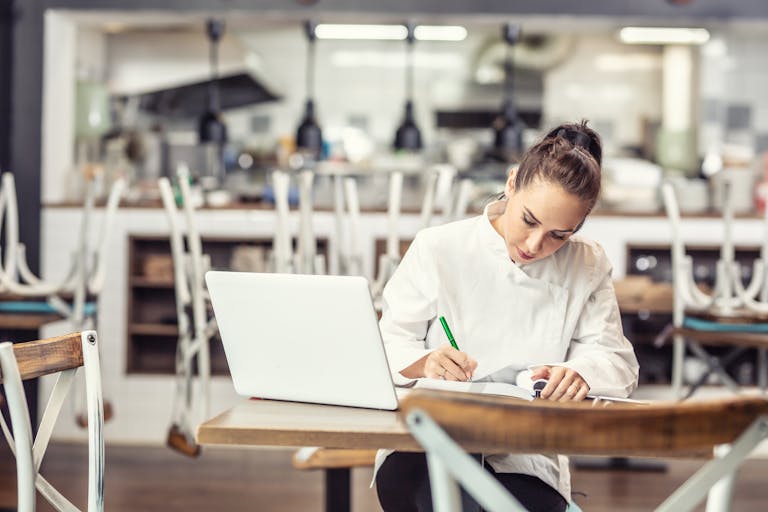 A chef sits in front of a computer writing a restaurant business plan