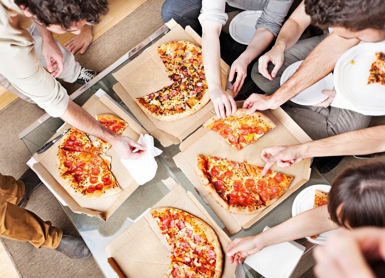 A group of people eating pizza together at home.