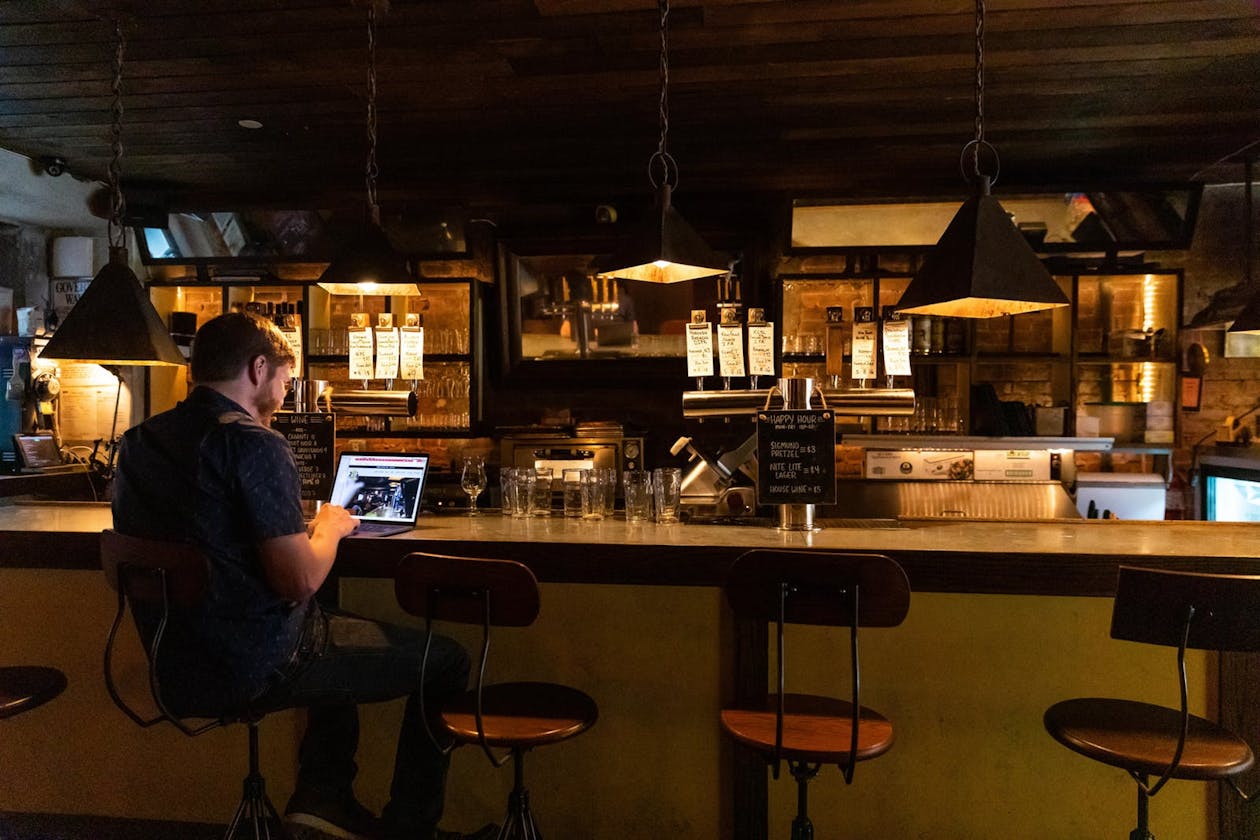 A man working on his laptop sitting at a wooden bar.